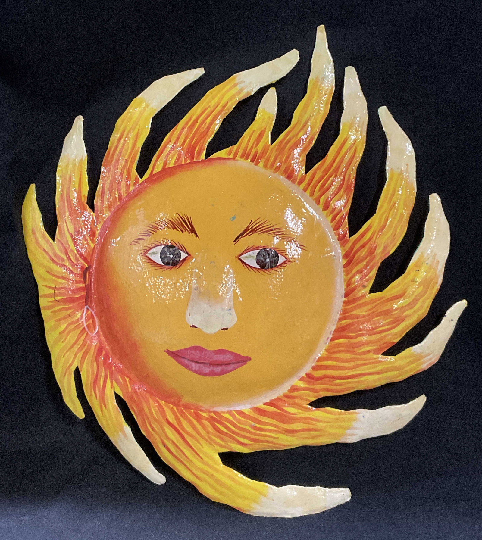 Painted Sun Face 13.25in Metal Wall Art HAITI: Painted Sun Face Metal Wall Art. Steel Material. Painted Yellow and Orange with Human-Style Features. Prominent Eyelashes. Made in Haiti. Some Wear to Paint. Measures app 13.25in H x 12in Diam. Sun Fa