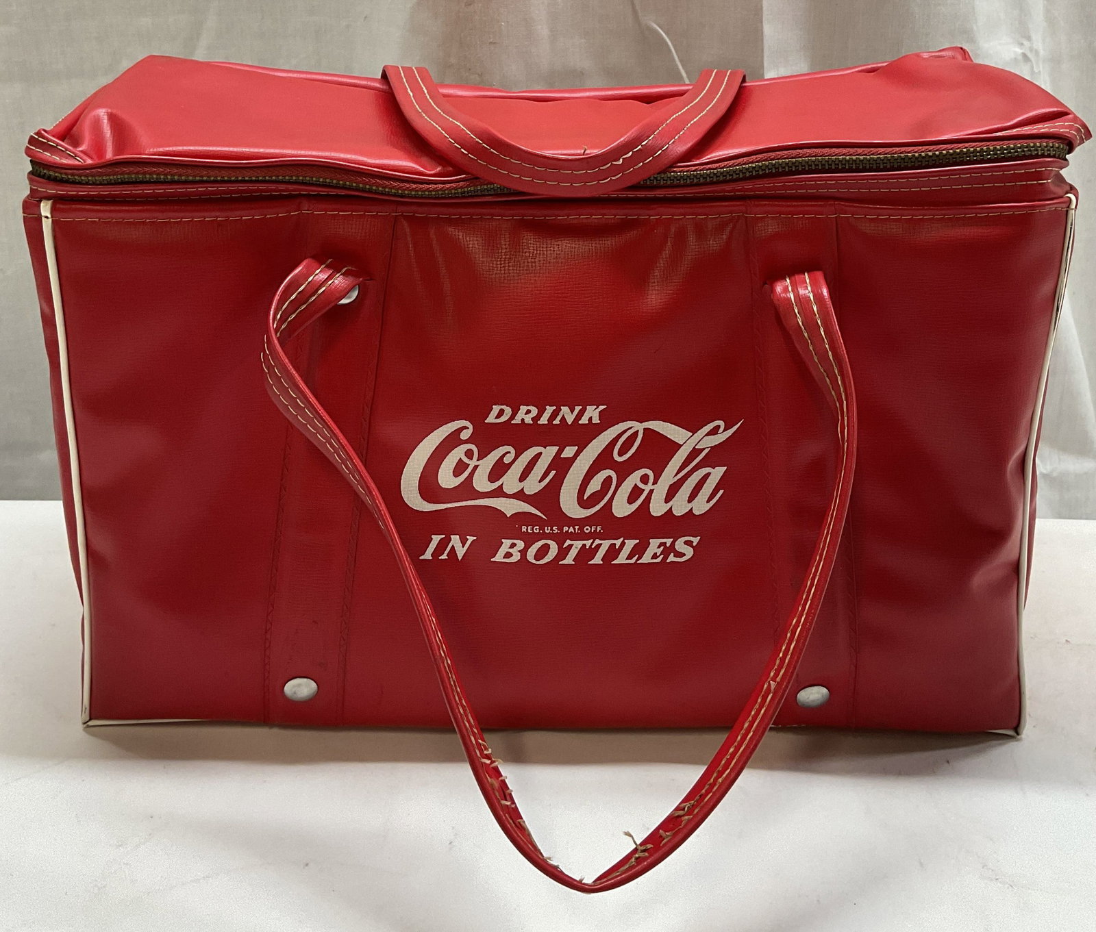Vntg Coca-Cola Cooler Bag: Vintage Coca-Cola bag features white lettering that reads Drink Coca-Cola In Bottles. White trim detailing. Handles at top. Surface wear consistent to age, use & exposure. Measurements: length 14.2in 