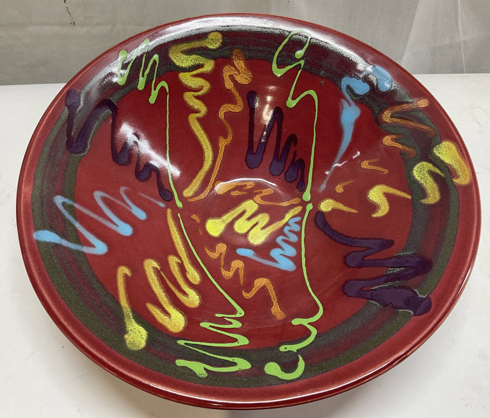 Lasser Red Craze Ceramic Bowl: Lasser ceramic bowl featuring multicolored abstract squiggles. Red background. Surface wear consistent to age, use & exposure. Signed & marked on underside. Reads, LA. Measurements: length 12.4In x