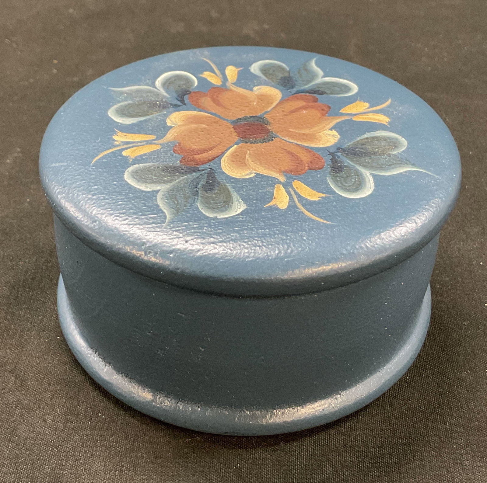Vintage Wooden Hand Painted Trinket Box Norway: Vintage wooden hand painted lidded trinket box. Made in Norway. Circular box. Painted blue with hand painted floral motifs in varying colors. Measures ht approx 2 inches diam approx 3.5 inches.