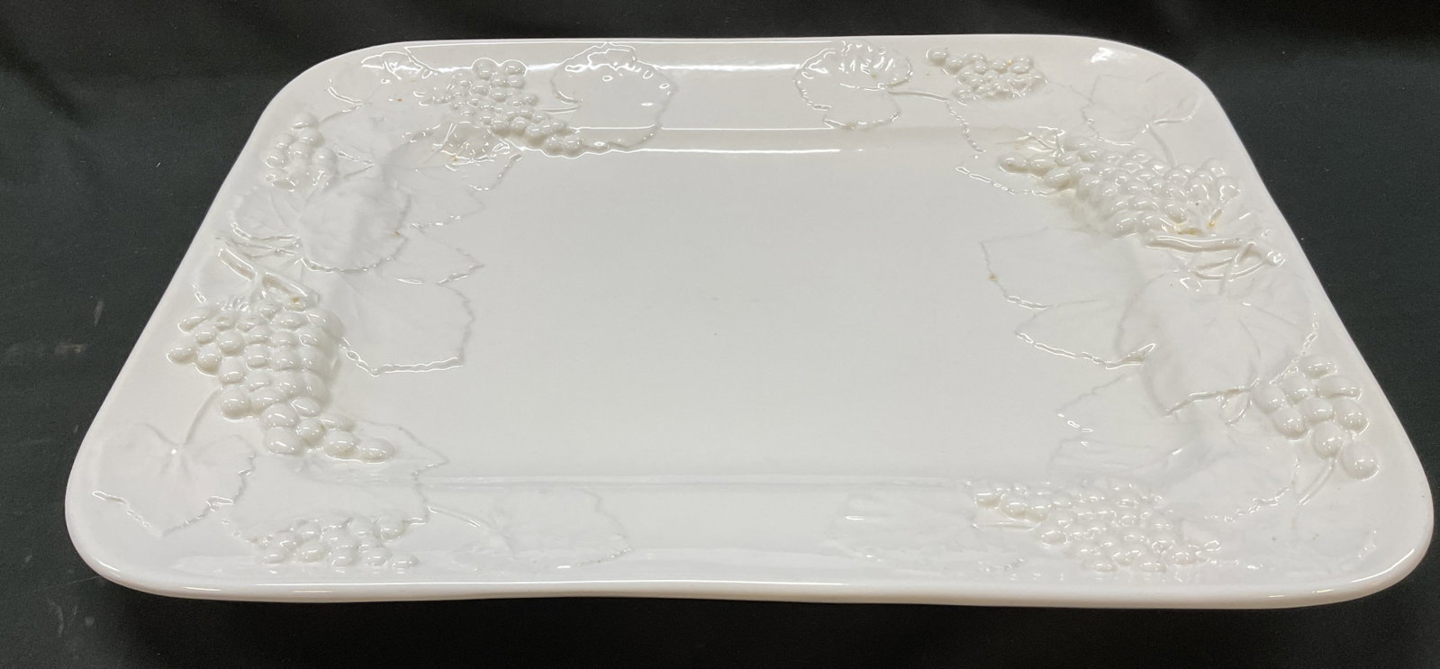 Elios Ceramic Grape Serving Tray Italy: Elios ceramic grape serving tray. Marked on underside, made in Italy. Rectangular tray. Embossed grapevine motifs. Glossy finish. Measures approx 13.5 x 17.5 inches. Chipping and scratching. Serving