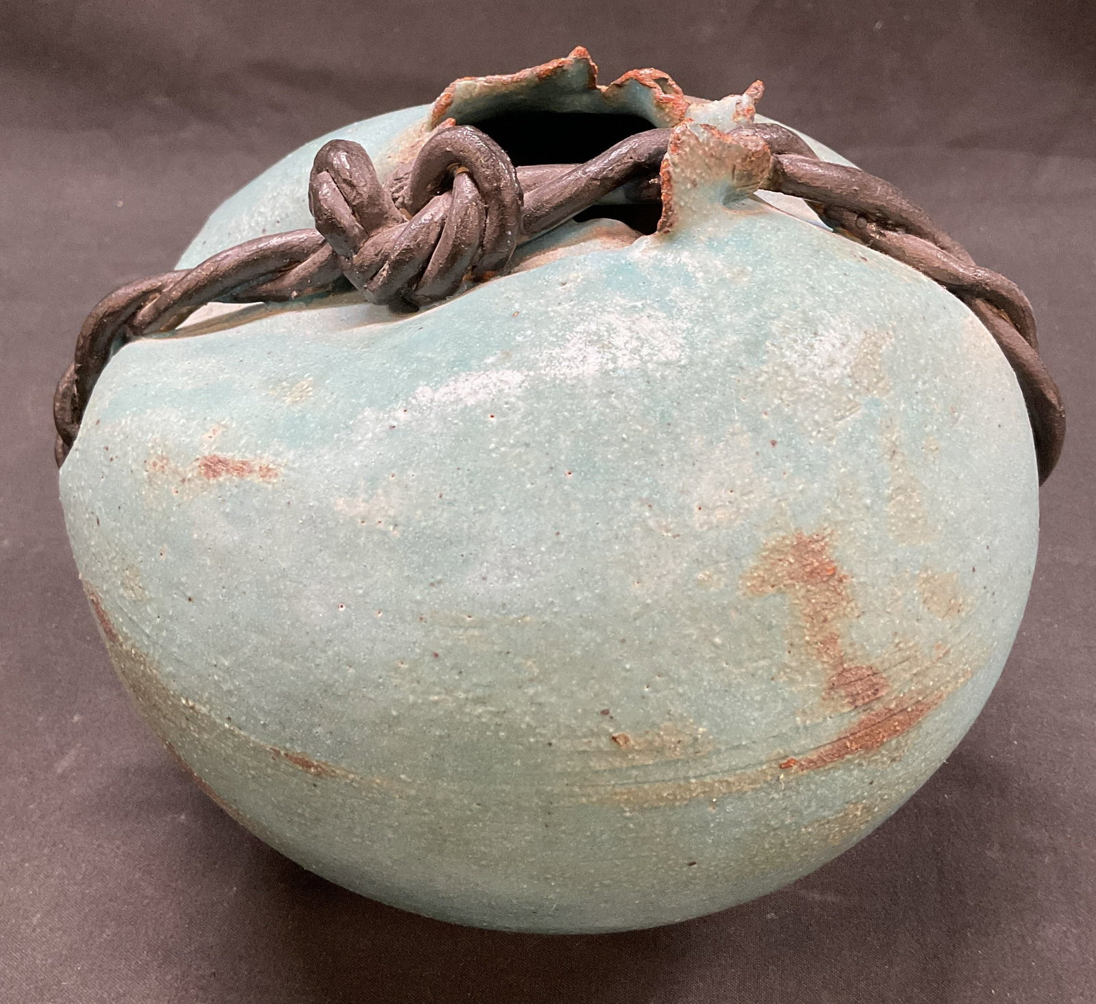 Sgnd Aqua Blue Pottery Vase: Signed aqua blue poster vase. Features a dark twisted rope like handle. Signed with initials on the bottom. Design in a globular form with rustic texture. Dented on one side, some rust and wear from a