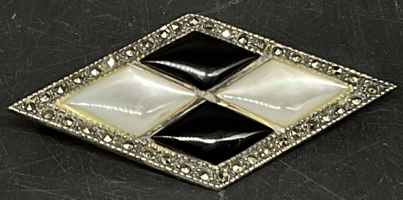 STERLING Silver Rhombus-Shaped Brooch: Sterling Silver Rhombus-Shaped Brooch. Marcasite Border. Rhombus-Shaped Black Onyx and White Mother-Of-Pearl Stones. Marked 925. Scratching and Tarnishing Present. Total Weight 7.2g. Measures app 2in 