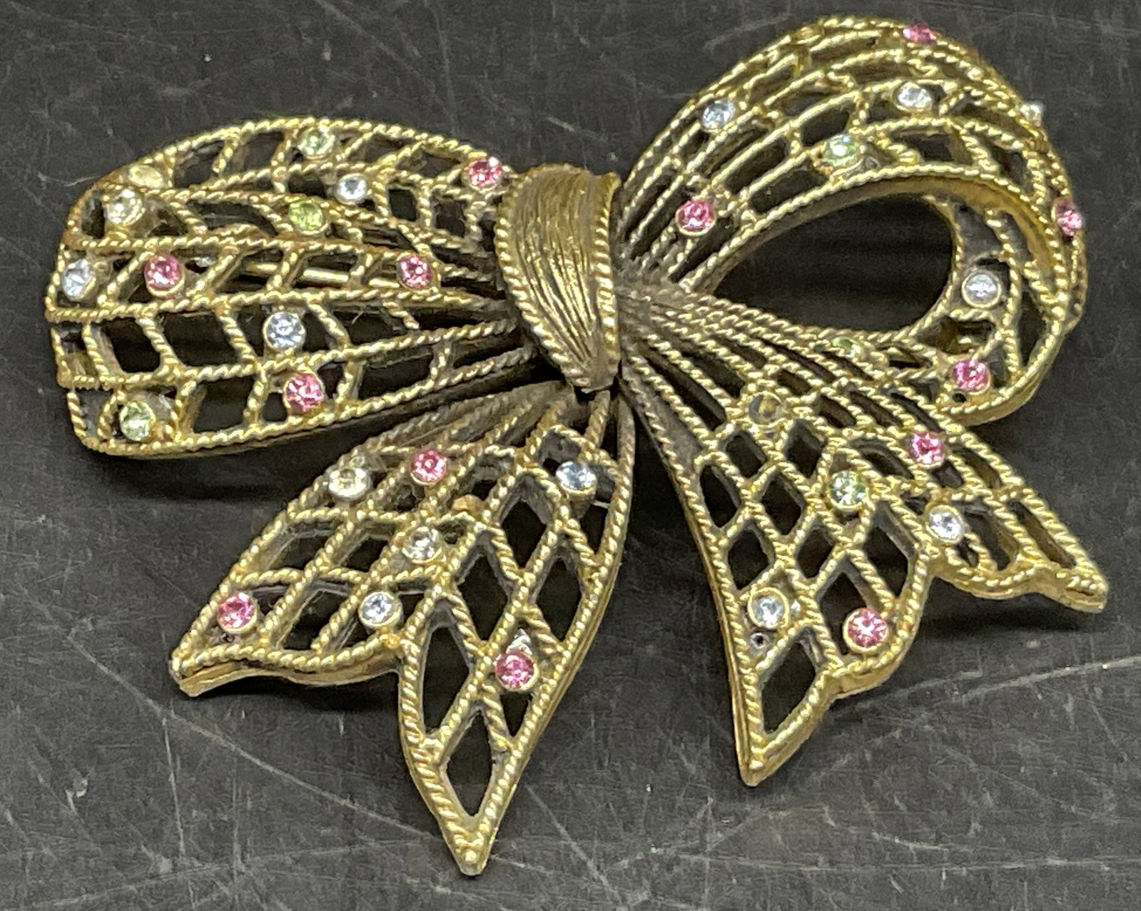 VINTAGE Gold-Toned Rhinestone Bow Brooch: Vintage Gold-Toned Bow Brooch. Latticework Design. Multicolored Pastel Rhinestone Accents. Some Missing Stones. Measures app 2in H x 2.25in L. Vintage Brooches, Gold-Toned, Bows, Rhinestones, Pins,