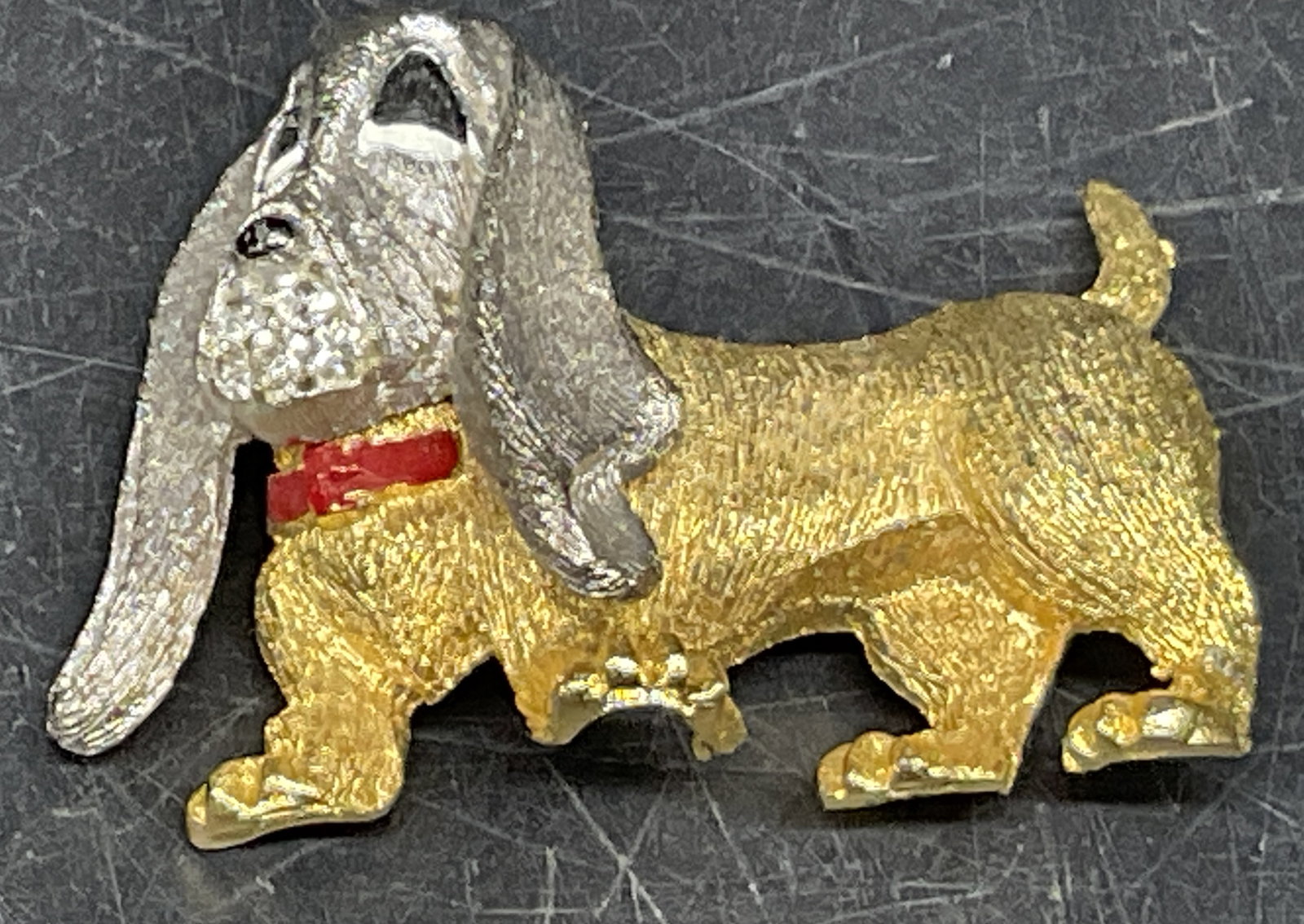 VINTAGE Basset Hound Figural Pin: VINTAGE Basset Hound Figural Pin. Silver-Toned Head with Gold-Toned Body Clear Rhinestones on Mouth. Red Collar. No Visible Markings or Brand. Head is Loose. Chipping to Plating on Back. Measures app