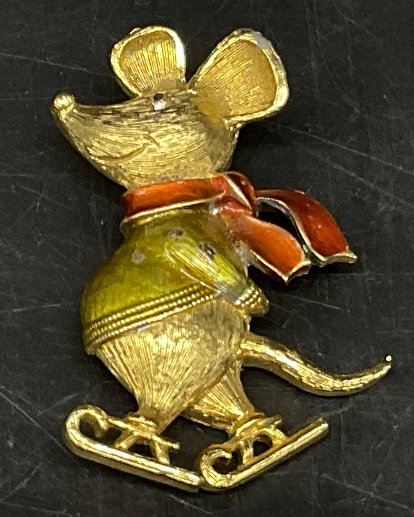 VTG Jonette Jewelry Co Ice Skating Mouse Brooch: Vintage Jonette Jewelry Co Gold-Toned Ice Skating Mouse Brooch. Green and Red Enamel Sweater and Scarf. Rhinestone Eye. Marked JJ. Wear to Plating and Enamel Present. Measures app 1.5in H x 1in L.