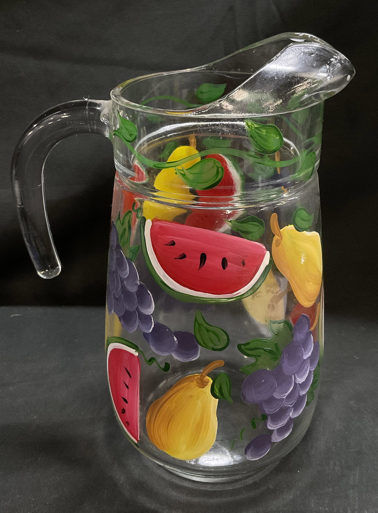 MCM Hand-Painted Fruit Clear Glass Pitcher FRANCE: Mid-Century Modern Clear Glass Pitcher. Hand-Painted Watermelon, Grapes, and Pears with Twisting Vine Design. Ice-Guard and Short Handle. Made in France. Condition Consistent With Exposure. Measures a