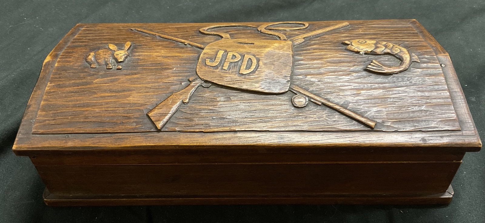 VTG 1935 SGND Robert Ames Hand-Carved Wooden Box: Vintage 1935 Signed Robert Ames Hand-Carved Wooden Box. Featured a Central Shield with Initials JPD, Crossed Rifles, a Fish, and a Rabbit. Some Chips and Cracks. Measures app 2in H x 8in L x 3.75in W.
