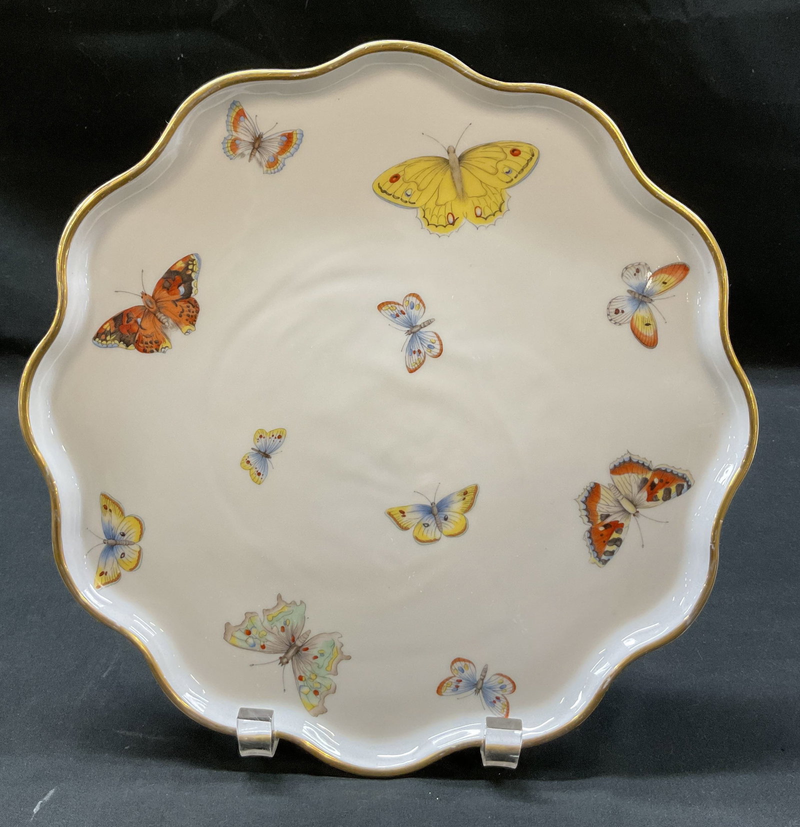 Limoges Porcelain Butterfly Tray France: Limoges porcelain butterfly tray. Marked on underside, made in France. Scalloped gilt edge. Various butterfly motifs in varying colors. Measures approx 10 inches in diameter. Scratching. Tray,
