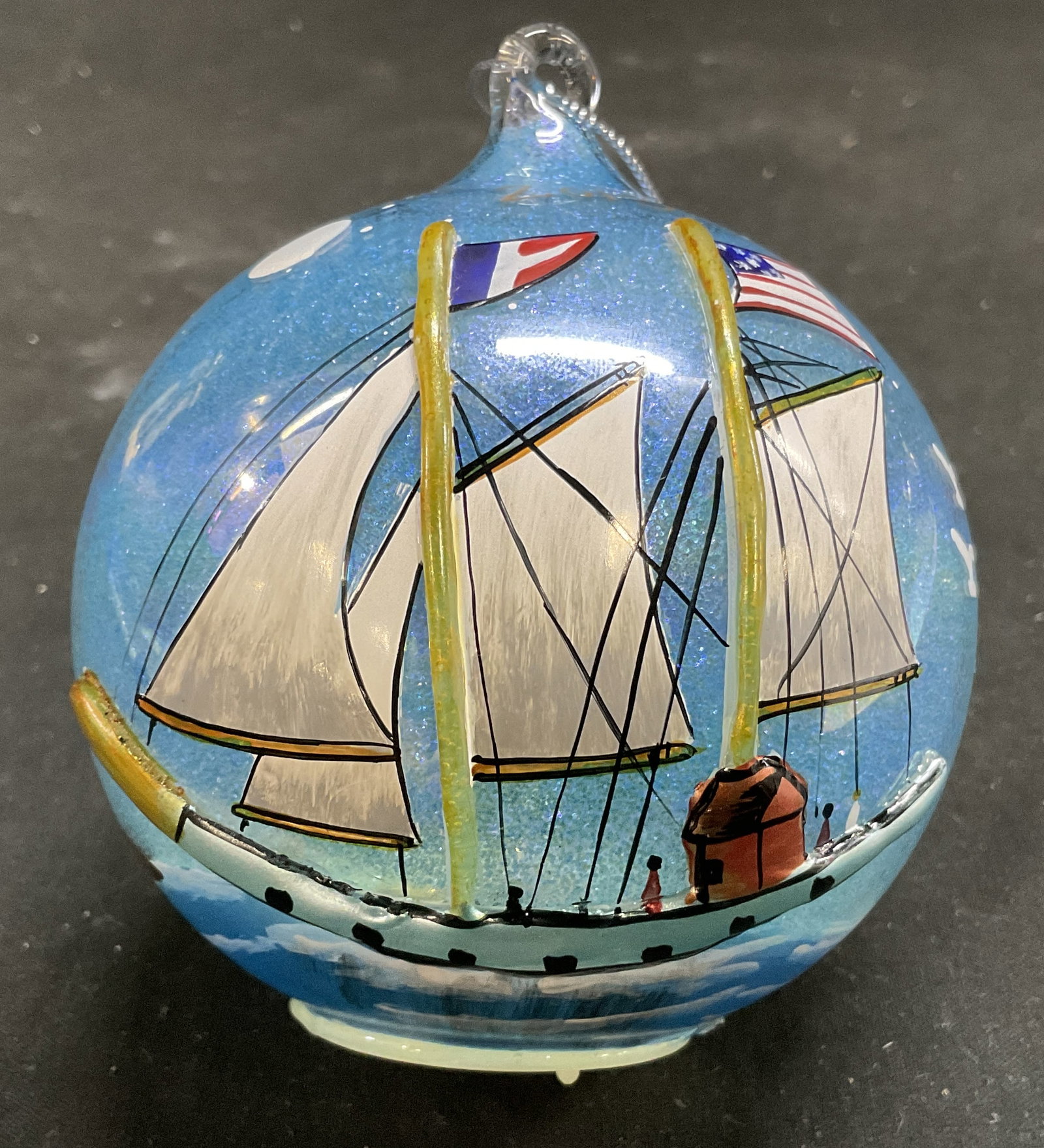 2013 Alessandra Hand-Painted RI Glass Ornament: 2013 Alessandra Collection Hand-Painted Newport, Rhode Island Glass Ball Christmas Ornament. Depicts Raised Relief Paintings of Seagulls, Sailboats, and Lighthouses on Glittery Blue Background. Light-