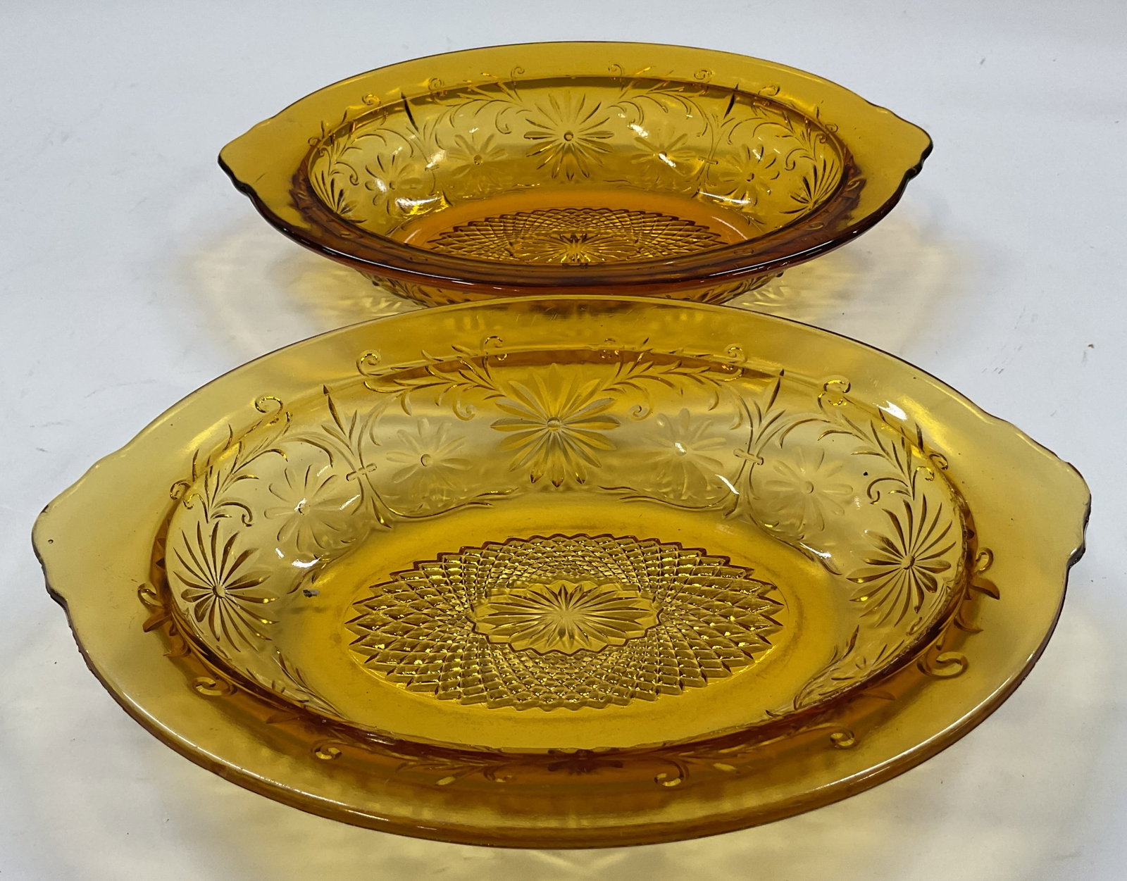 Set 2 Indiana Glass Amber Daisy Oval Veg Bowls: Set of 2 Indiana Glass amber Daisy oval vegetable bowls. Oval shaped bowl. Amber color. Daisy pattern, cut floral and geometric motifs. Measures approx 7 x 10 x 2 inches. Some scratching. Vegetable