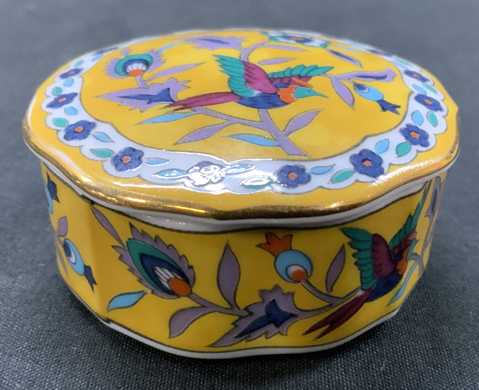 Vtg 1983 Takashi Silk Road Porc. Trinket Box US: Vintage 1983 Takashi Trading Silk Road Porcelain Trinket Box, San Francisco, USA. Multi lobed scalloped body. Yellow background with chinoiserie style illustration of paradise bird nestled among flora