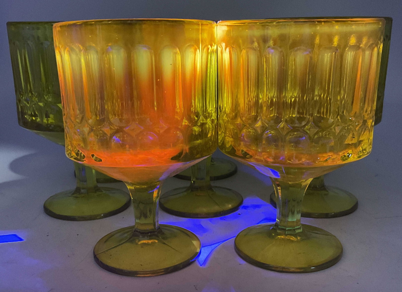 St8 CADMIUM Indep Glass Sculptural Topaz Goblets: Set of 8 Mid-Century Modern Independence Glass Sculptural Topaz Yellow Goblets. Thumbprint and Geometric Designs. Made of Cadmium Glass Which Glows Orange Under UV Light. Some Color Loss. Measures app
