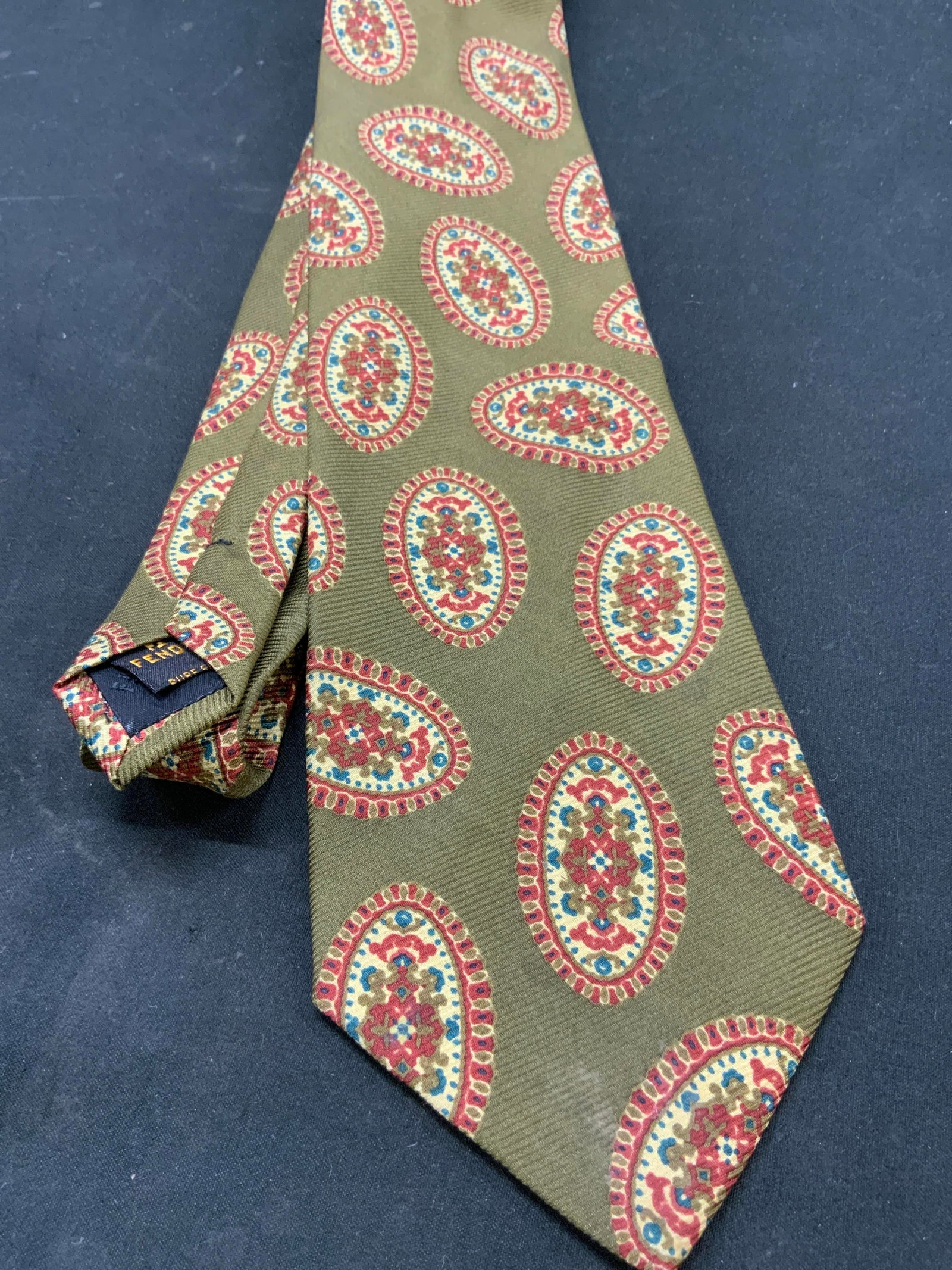 Vtg FENDI Cravatte Silk Medallion Necktie, Italy: Vintage FENDI Cravatte collection 100% silk Mens necktie. Medallion pattern. Olive green with terracotta, blue, cream medallions. FENDI made in Italy tag on reverse side. Measures approx. 58x3.5 in We
