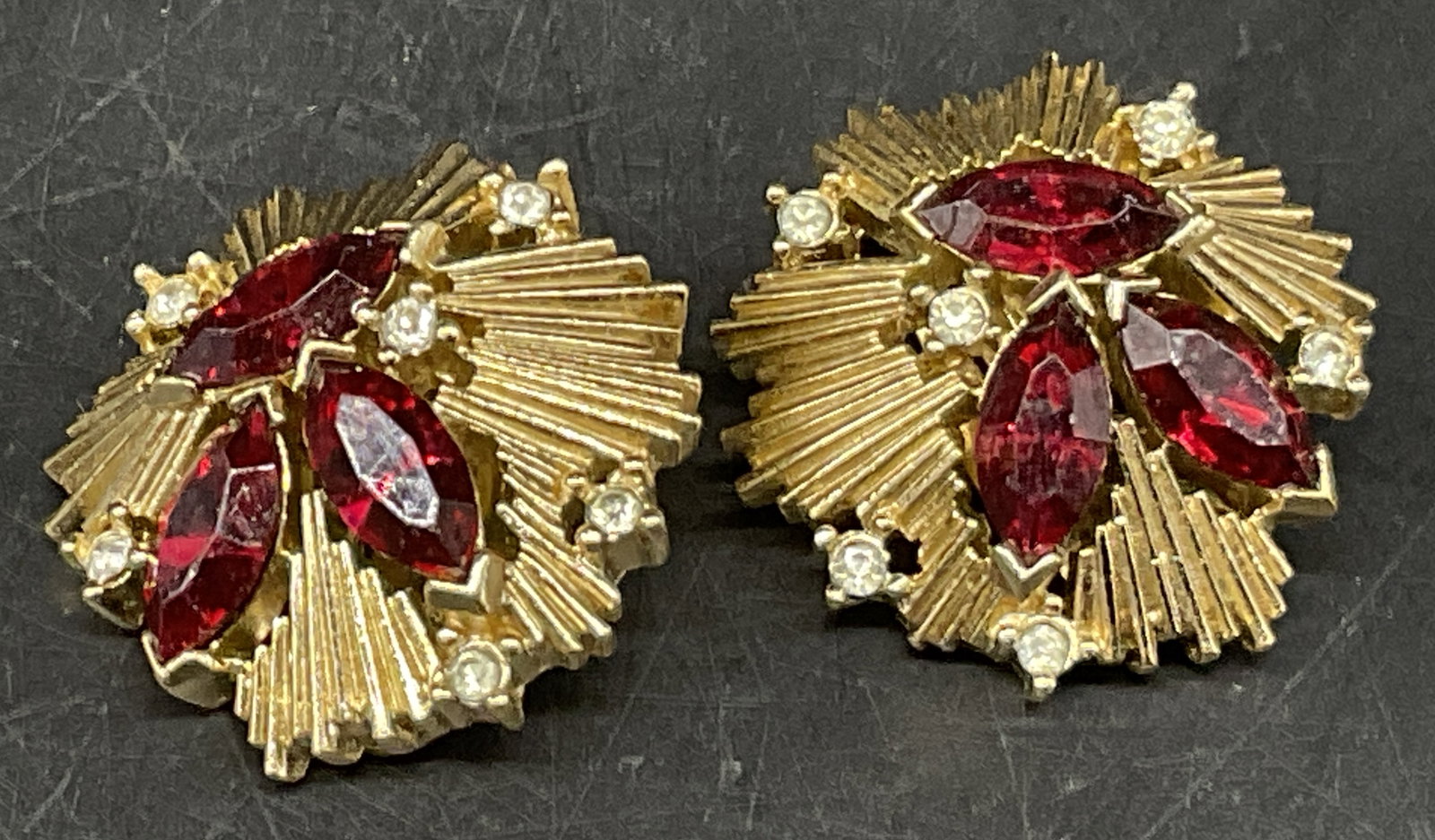 Pair VTG Crown Trifari Starburst Clip-On Earrings: Pair of Vintage Circa 1950s-1960s Crown Trifari Clip-On Earrings. Gold-Toned Starburst Pattern with Clear Rhinestone Chatons and Clustered Red Marquise-Cut Rhinestones. Some Corrosion. Measures app 1i