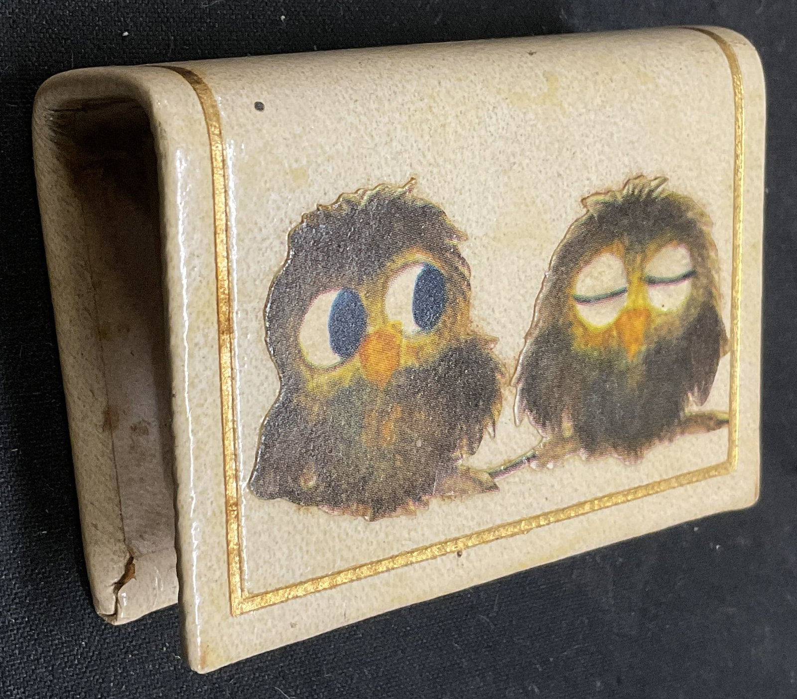 VINTAGE Baby Owl Book Matchbox Sleeve: Vintage Matchbox Sleeve. Cream Leather-Style Book-Shaped with Decoupage Art of 2 Baby Owls. One Wide Awake and One Sleeping. Fraying, Scratching, and Staining Present. Measures app 2.5in H x 2in L.
