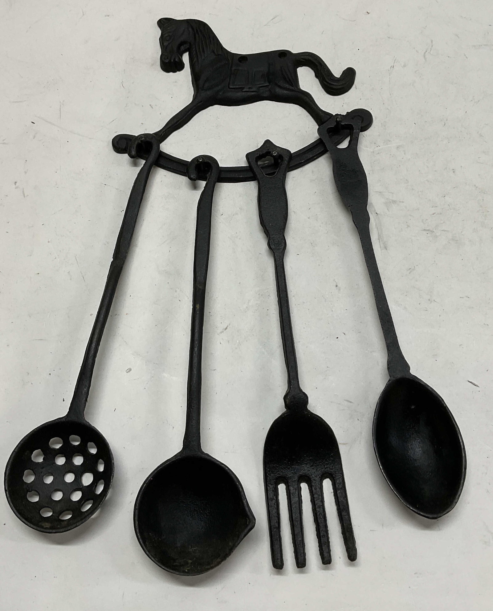 Cast-Iron Rocking Horse Utensil Holder w/ Utensils: Black Coated Cast-Iron Rocking Horse Utensil Holder w/ Utensils. Includes a Strainer Spoon, A Ladle, A Serving Fork, and a Serving Spoon. Condition Consistent with Exposure. Horse Measures app 6in H