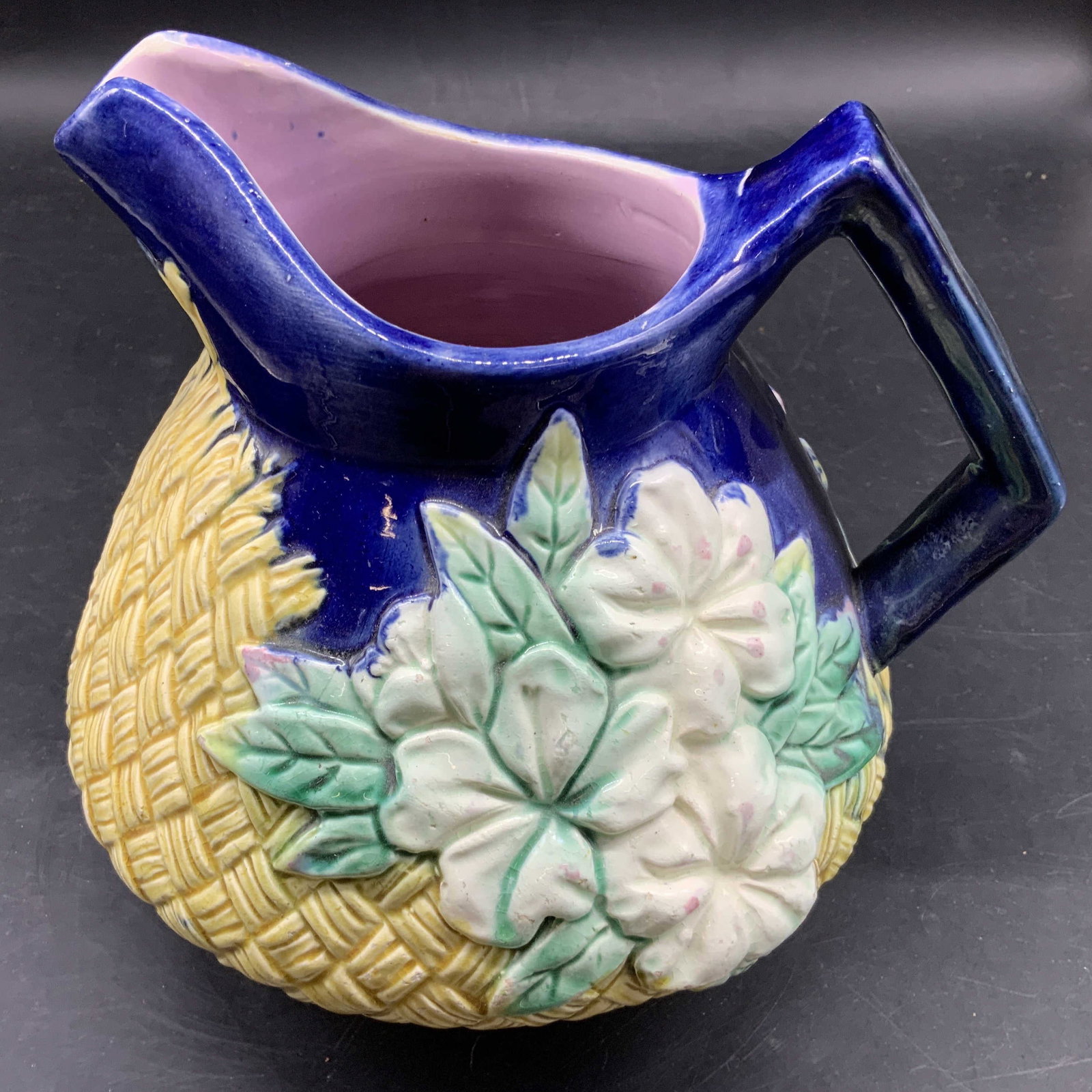 Antique English Majolica Ceramic Pitcher: Circa 1890 this antique majolica pottery ceramic pitcher features a yellow cross hatched textured basket weave body with applied white and green floral decorations, finished with a distinctive cobalt 