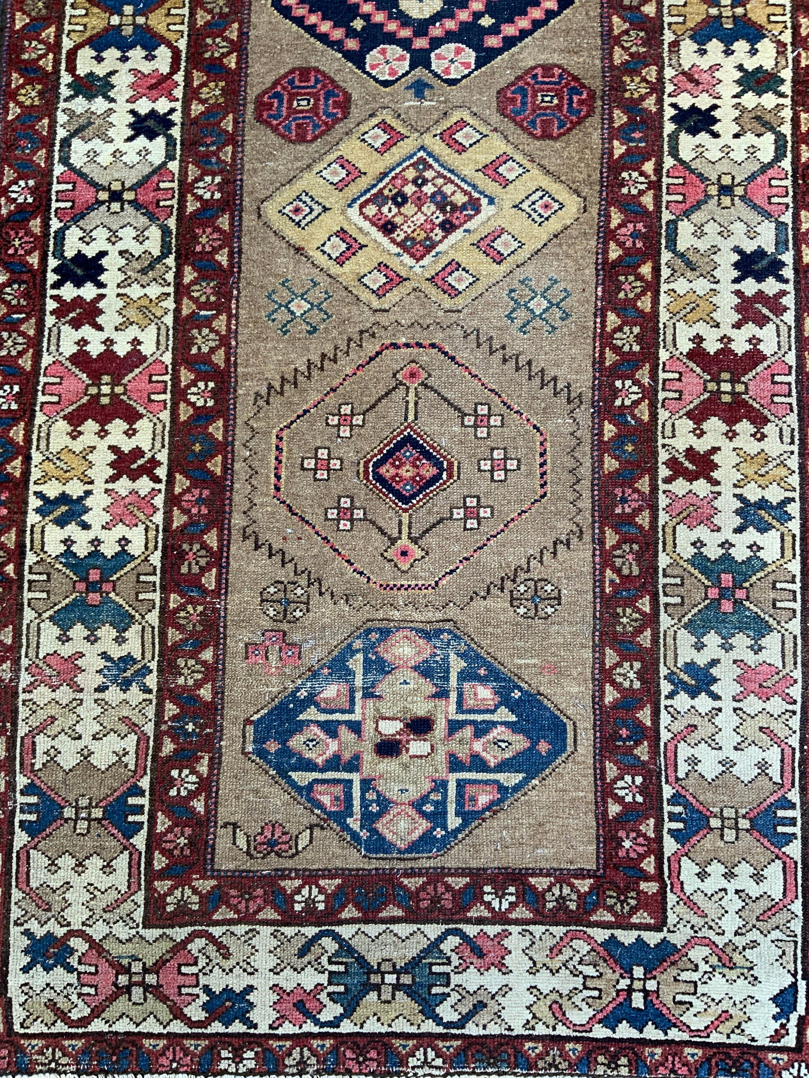 Vntg Persian Saran Carpet Runner: Vintage Persian Sarah runner , a hand knotted wool rug featuring tribal medallions in warm camel hair tones and pink and blue accents, measures 29 by 98 inches