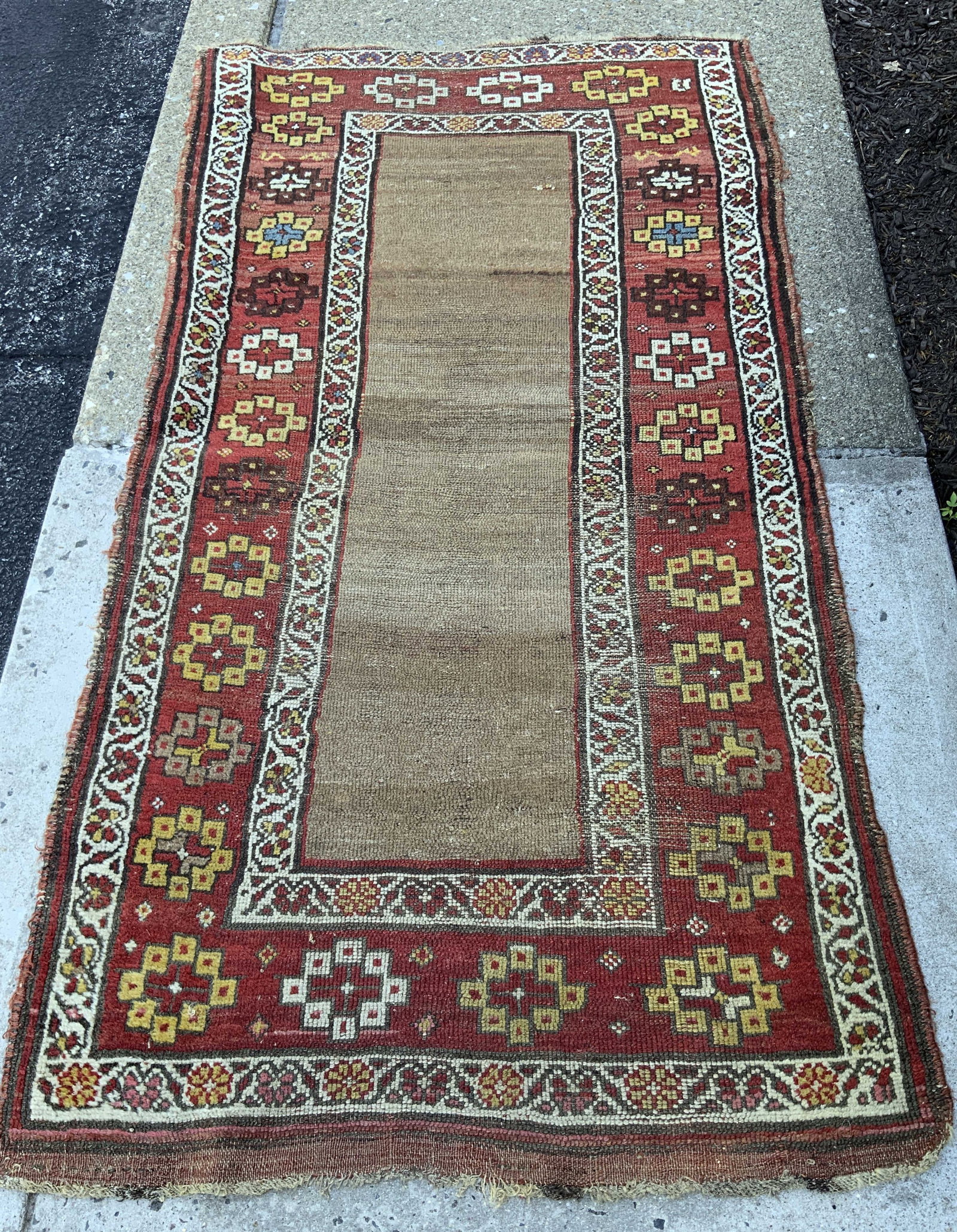 Antique Kurdish Tribal Wool Rug: Antique Kurdish Tribal Wool Rug features a distinct camel colored field and geometric borders, framed by a crimson border with multi color tribal rosettes, geometric stars, and interlocking vine