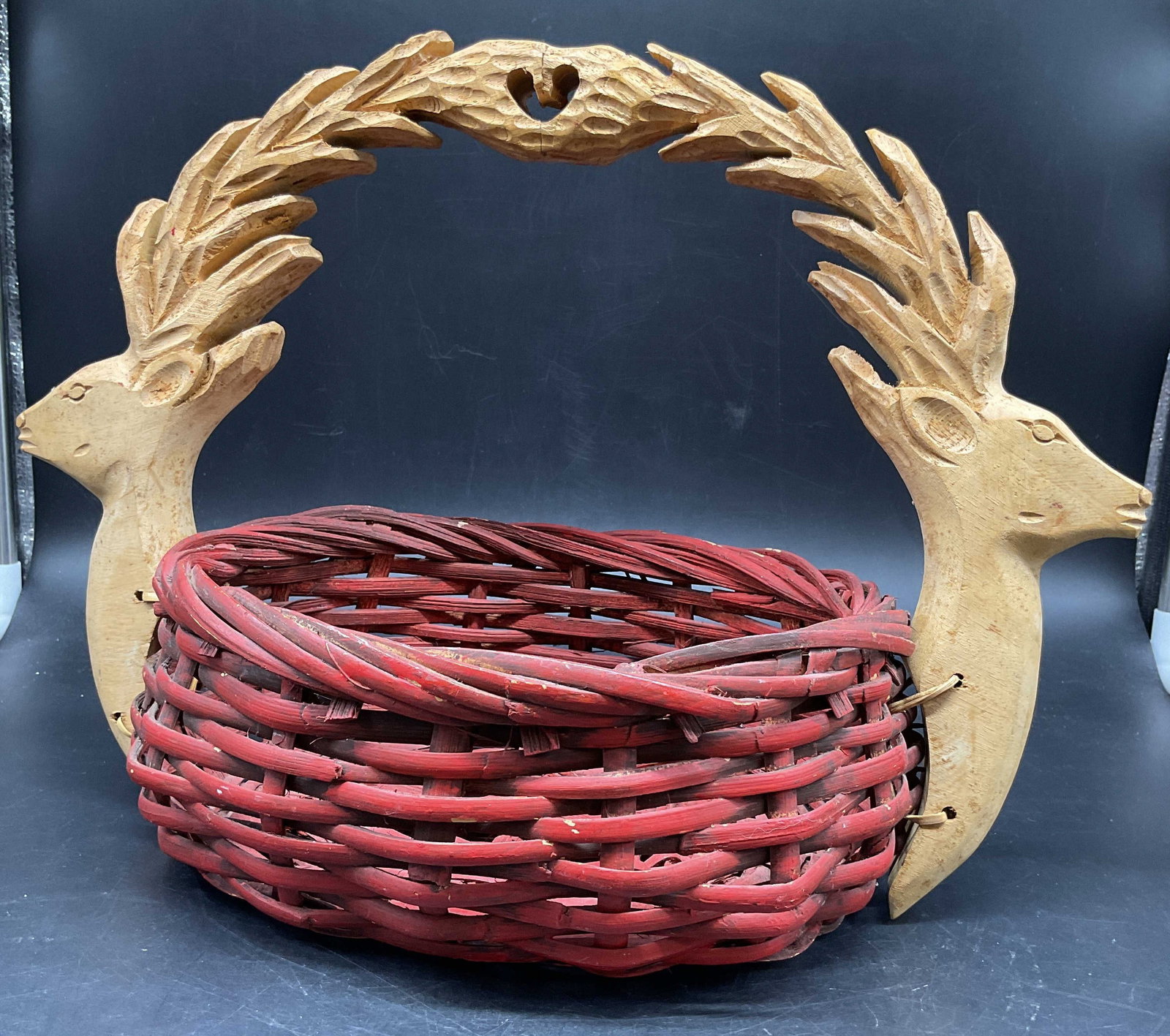 Carved Wood Deer Handle Basket: Red twined wood basket with carved deer heads and carry handles, measures ht 11 inches, length 15 inches width 8.5 inches, folk are , heads affixed with twined binding