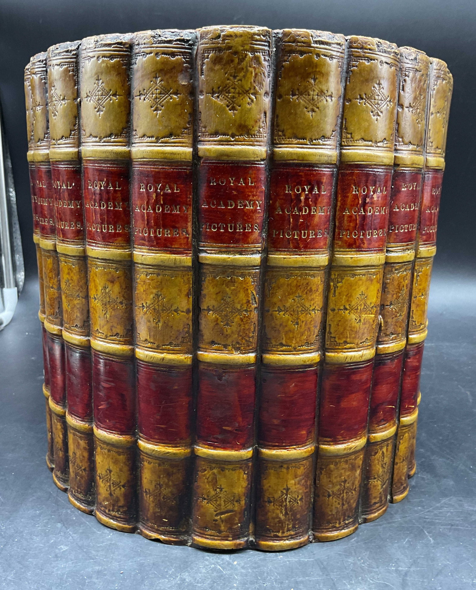 Trompe Loeil Book Binding Waste Basket, England: Label affixed to underside reads the original book works limited , handcrafted in Gloucestershire, England, Trompe L Oiel Book antique style book binding ringed waste basket, bindings read Royal