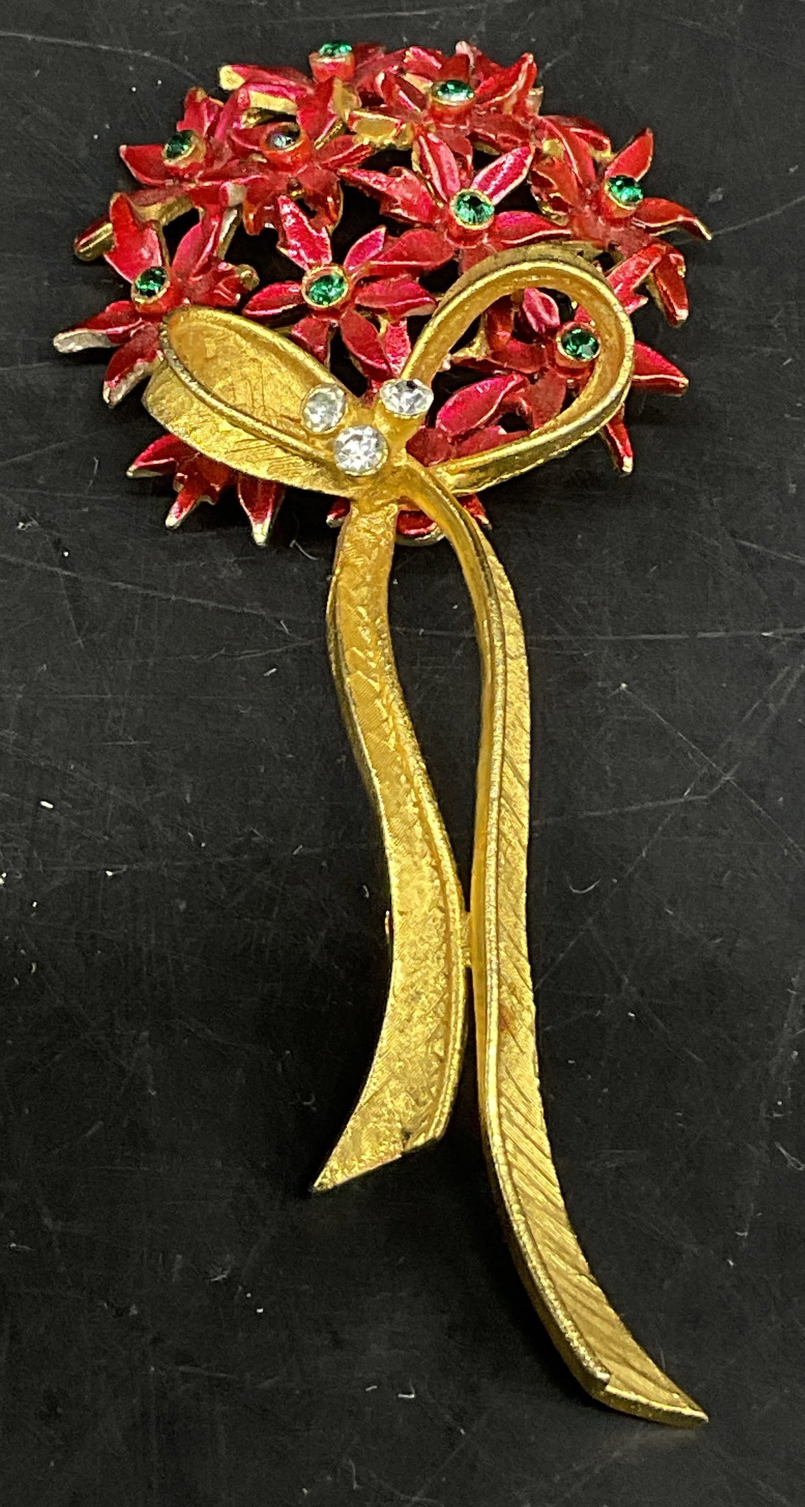 VTG 60s Mylu Red Enamel Poinsettia Bouquet Brooch: Vintage Circa 1960s Mylu Flower Bouquet Brooch. Red Enamel Poinsettia Flowers with Small Green Rhinestone Accents. Gold-Toned Ribbon Bow with White Rhinestones. Condition Consistent With Exposure. Mea