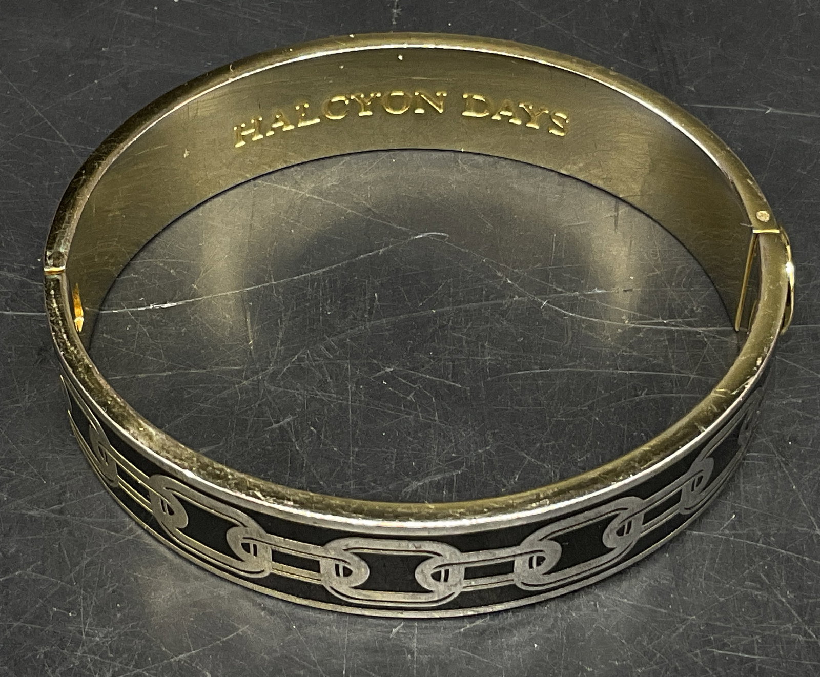 Halcyon Days 18KGold-Plated Enamel Bangle ENGL: Halcyon Days 18K Gold-Plated Bangle. Skinny Chain on Black Enamel Design. Opens on Hinge. England. Scratching Present. Measures app 2.25in Diam When Closed. Halcyon Days, Gold-Plated, Bangle, Chain, E