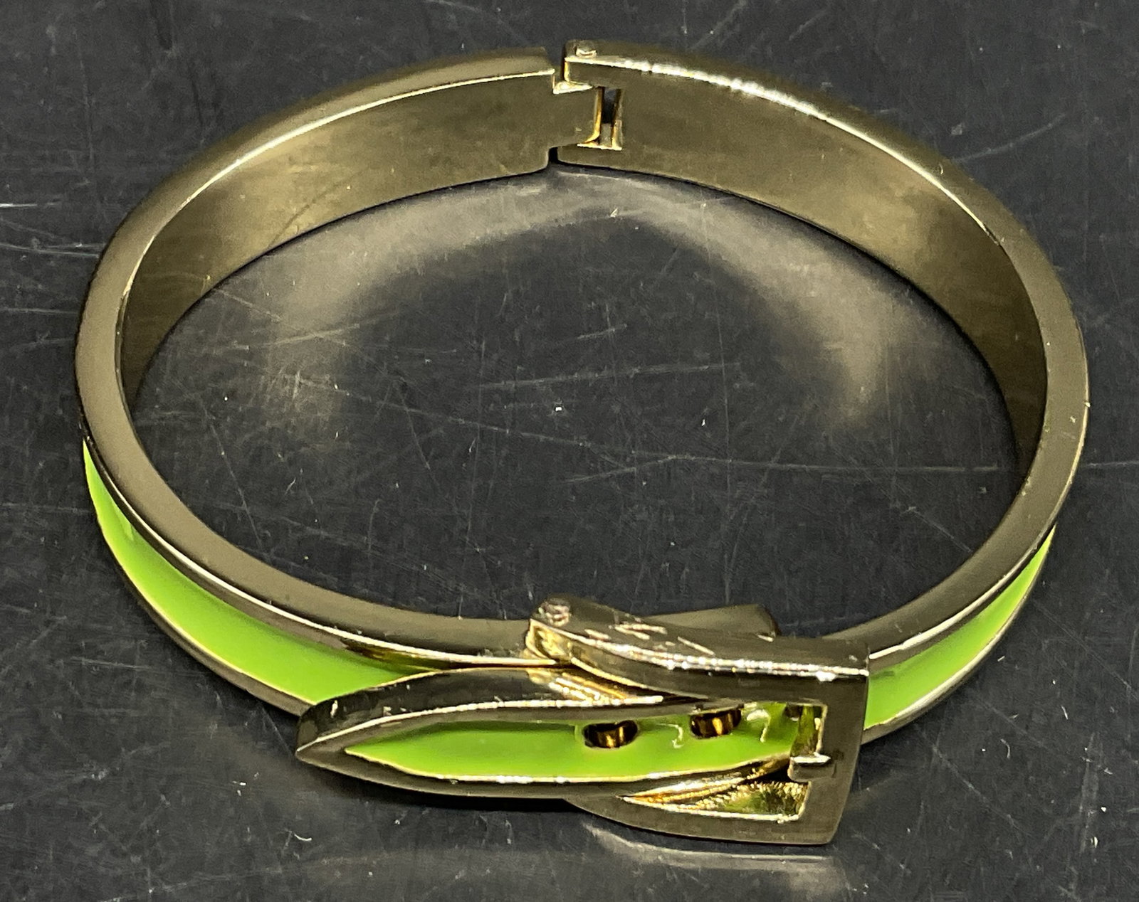 1960s Style Lime Green Enamel Belt Buckle Bangle: Gold-Toned and Lime Green Enamel Belt Buckle Bangle. 1960s Style Design. Opens on Hinge. 3 Different Adjustments. Scratching Present. Measures app 2.75in Diam Largest and 2.5in Diam Smallest. Gold-Ton