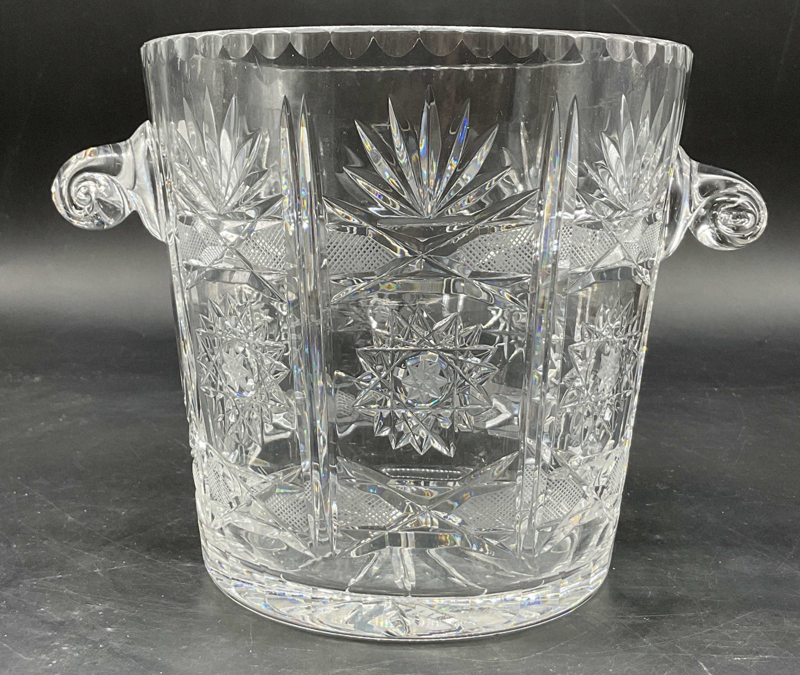 Vintage Cut Crystal Ice Bucket: Vintage cut crystal ice bucket, champagne cooler. Applied scroll handles. Scalloped accent. Cut geometric and star patterns. Measures ht approx 6 inches diam approx 6 inches. Scratching. Ice bucket, c
