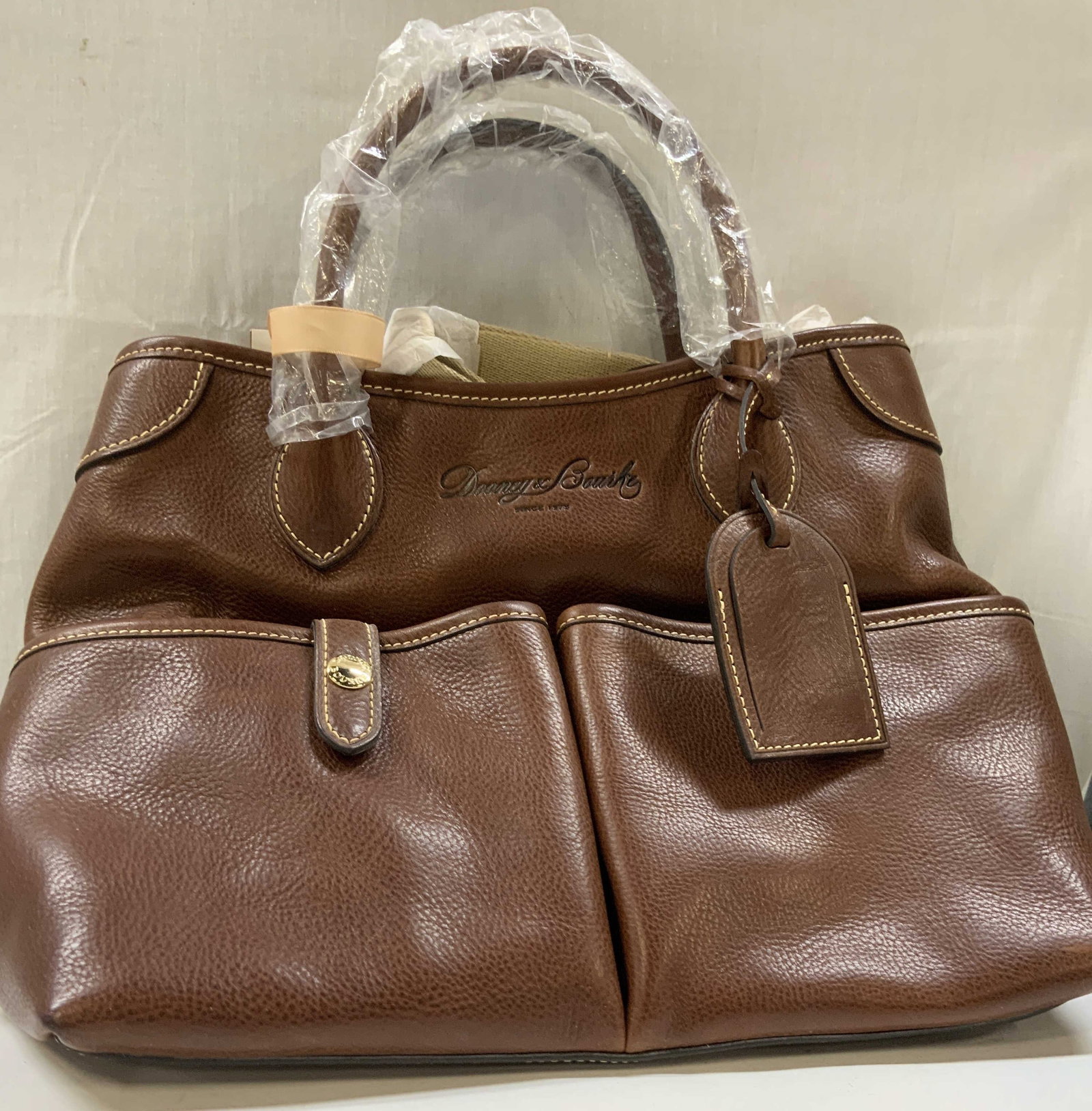 Dooney&Borke Florentine vacchetta leather bag NWT: Dooney&Borke Florentine vacchetta leather bag. New With Tags. Bag features two front snap pockets and gold toned hardware. Includes two leather hand straps as well as a cloth shoulder strap that can b