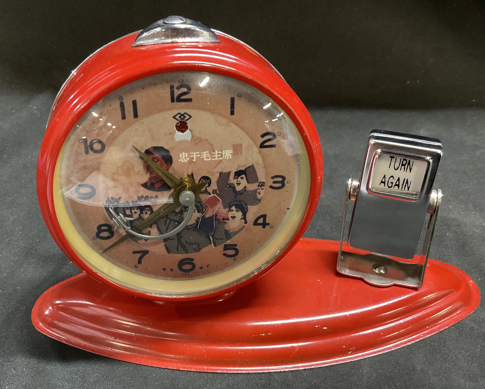 VTG Chinese Propaganda Chairman Mao Clock: Vintage Circa 1970s-1990s Chinese Cultural Revolution Chairman Mao Animated Propaganda Alarm Clock with Built-In Turn Again Flip Calendar. Red Steel Frame. Illustrations of Mao Zedong with a Crowd of 