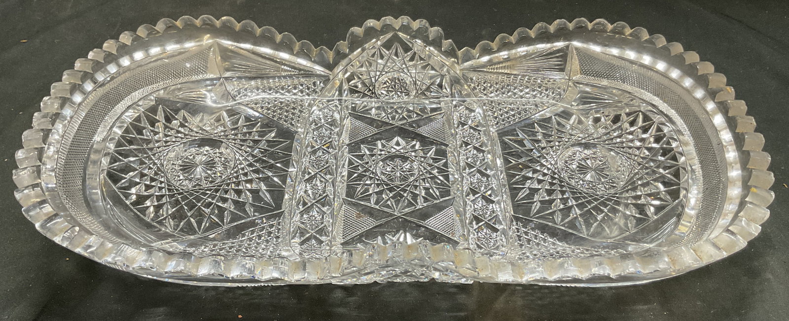 American Brilliant Period Cut Glass Serving Dish: American Brilliant Period cut glass serving dish. Scalloped sawtooth rim. Unique oval shape. Geometric hobstar fan and starburst motifs. Piece has some weight. Measures approx 8.5 x 15 x 2.5 inches. S