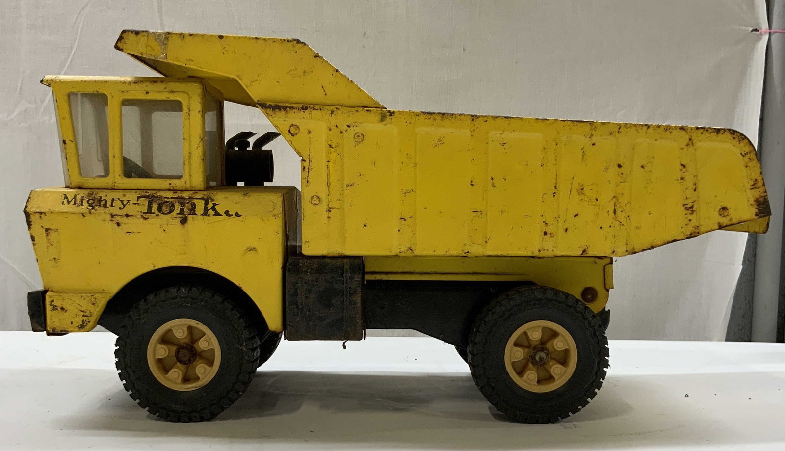 Vntg Mighty Tonka pressed steel dump truck 1970: Vintage Mighty Tonka pressed steel dump truck. From the 1970s. Model XBM-975. Featuring a yellow cab and bed with black duel wheel hubs. Rust from age and use. Measures app 10 in height, app 18 in len