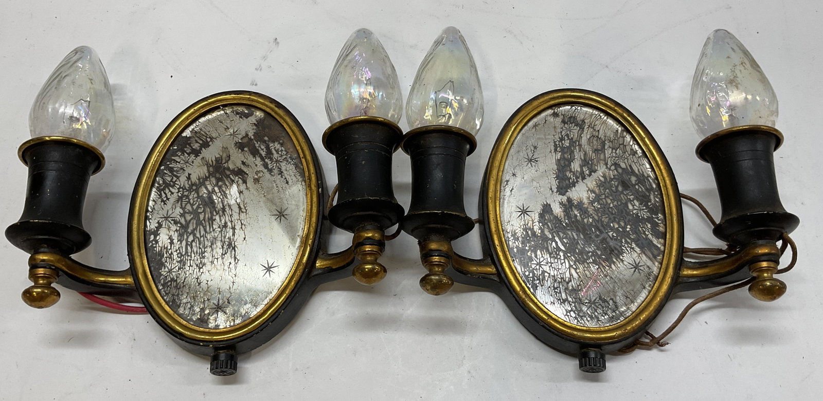 Pair Vintage Double Arm Mirrored Wall Sconces: Pair of vintage double arm mirrored wall sconces. Black brass toned metal frame. Oval shaped mirror with star accents. Measures approx 7 x 8.5 inches. Not tested for function, sold as is. Wear and scr