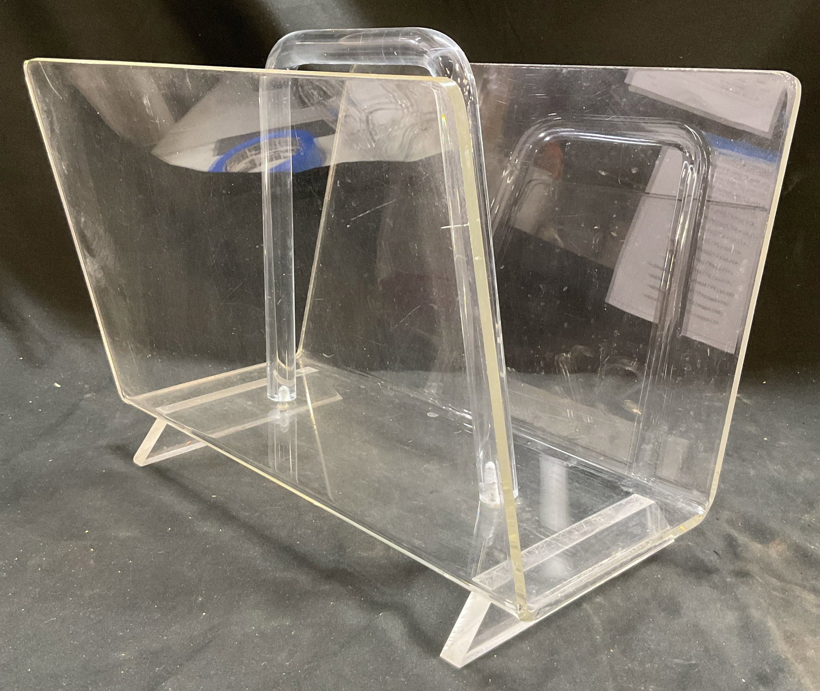 Vintage Clear Acrylic Footed Magazine Rack: Vintage clear acrylic footed magazine rack. Footed on underside. Minimalist two section design with built in central handle. Measures approx 10 x 14 x 12 inches. Scratching and screw needs tightening.