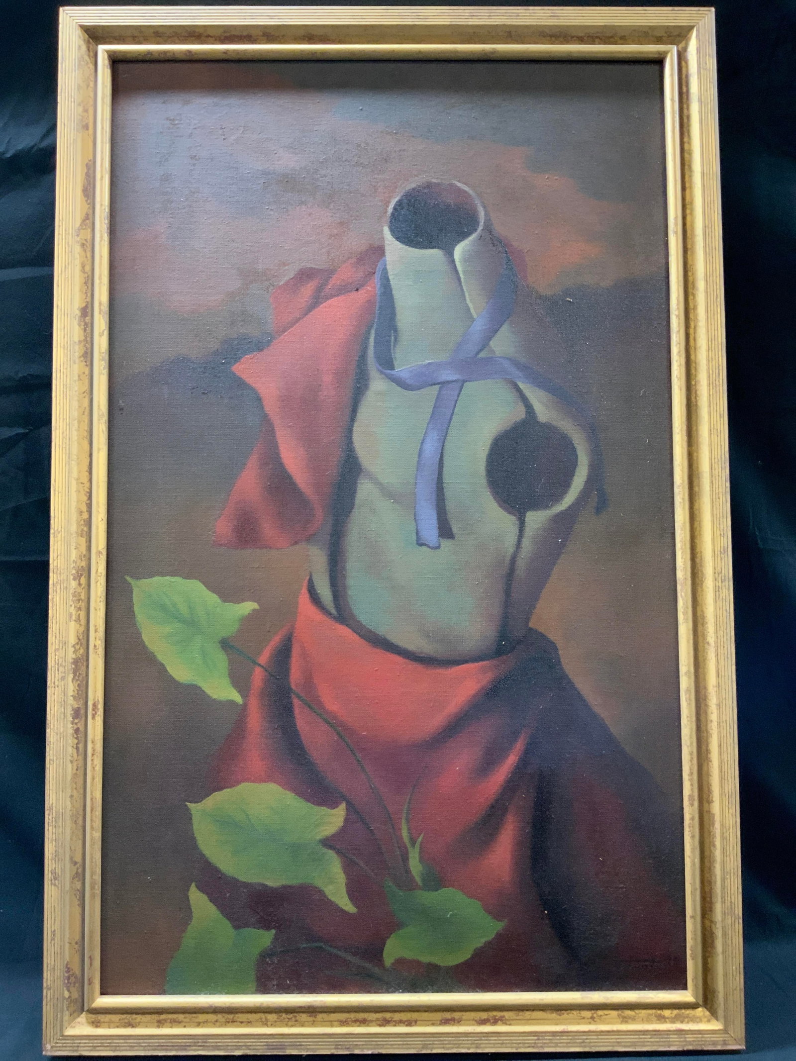 Surrealist Torso Mannequin Oil Painting Framed: Surrealist style oil painting on canvas. Stylized hollow dress form mannequin torso draped with red fabric cloak and accented by a purple ribbon tied around the neck. Green leafed plant towards center