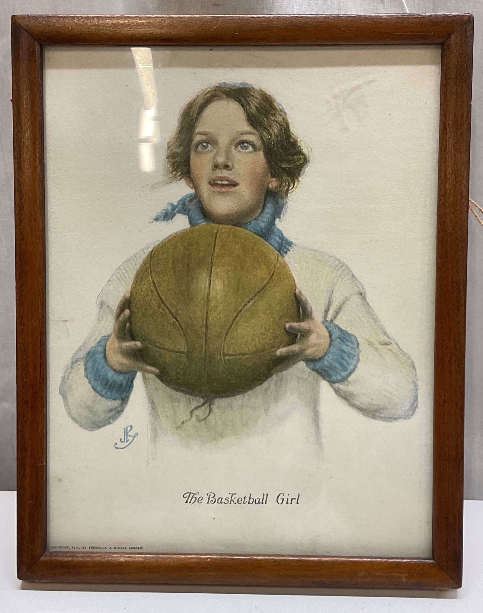 1910 JR The Basketball Girl Framed Lithograph: The Basketball Girl framed offset lithograph. Signed JR. Copyright 1910 by Frederick A Stokes Company, replica. Back of frame reads From C Gemignani Fine Art Department Griffin Block Room 10 Newburypo