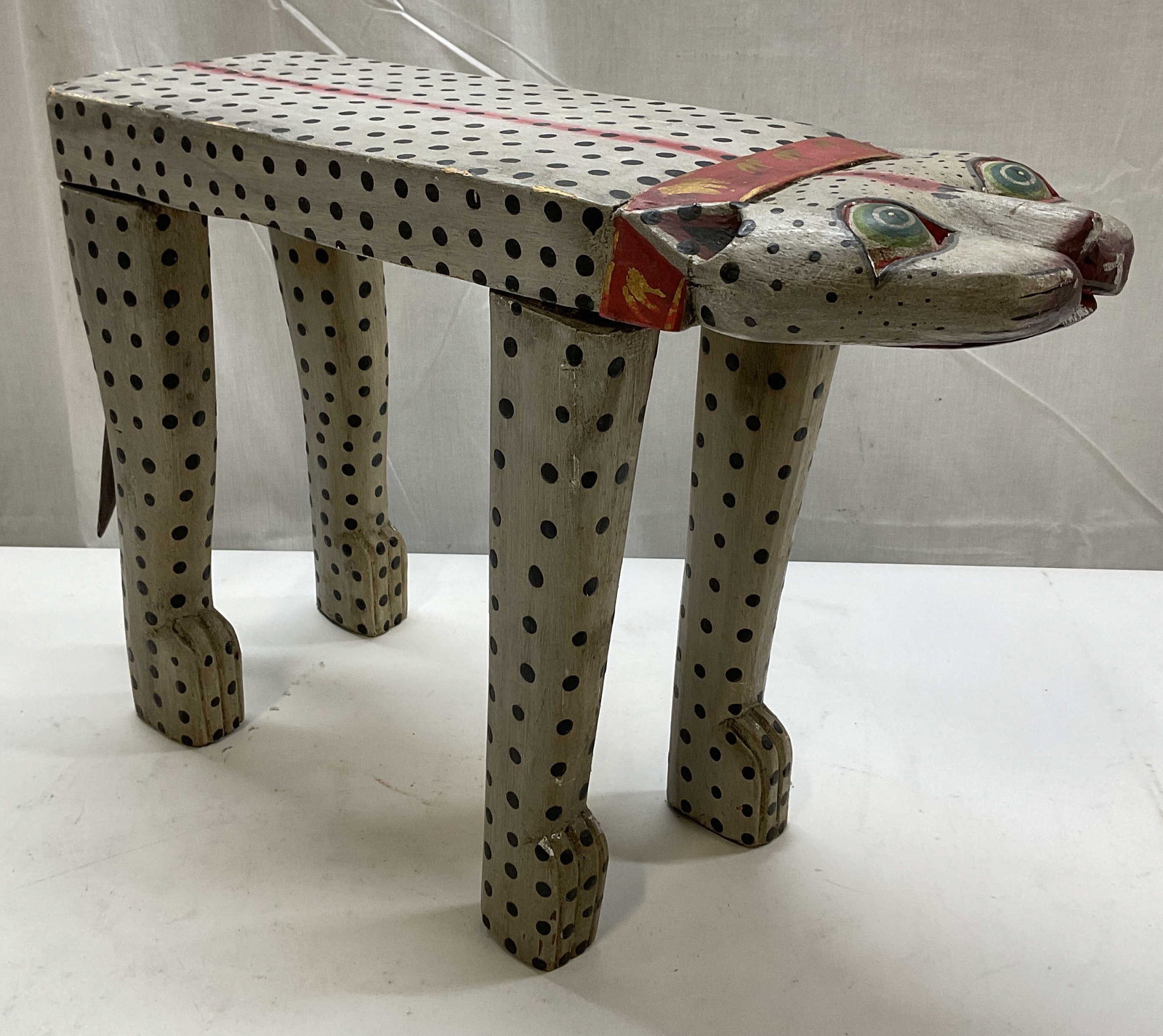 Vintage Balinese Folk Art Wooden Plant Stand: Vintage Balinese folk art wooden plant stand. Hand made and hand painted. Whimsical animal figure. Long top, four legs, tail. Black polka dots with red stripe. Carved details and features. Measures ap