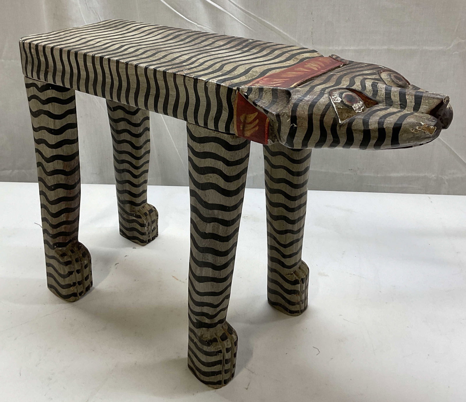 Vintage Balinese Folk Art Wooden Plant Stand: Vintage Balinese folk art wooden plant stand. Hand made and hand painted. Whimsical animal figure. Long top, four legs, tail. Black wavy lines with red stripe. Carved details and features. Measures ap