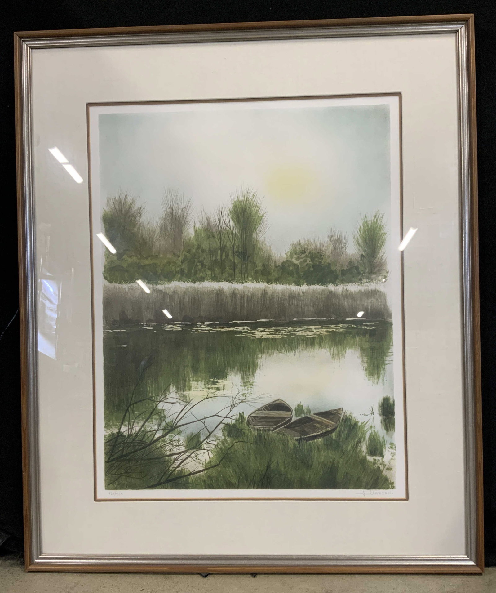 Sgnd Lakeside Rowboats Lithograph, Framed: Late 20th century color lithograph capturing hazy lakeside landscape scene. Composition illustrates two empty wooden rowboats nestled along a grassy shoreline with dark reflections cast upon the still
