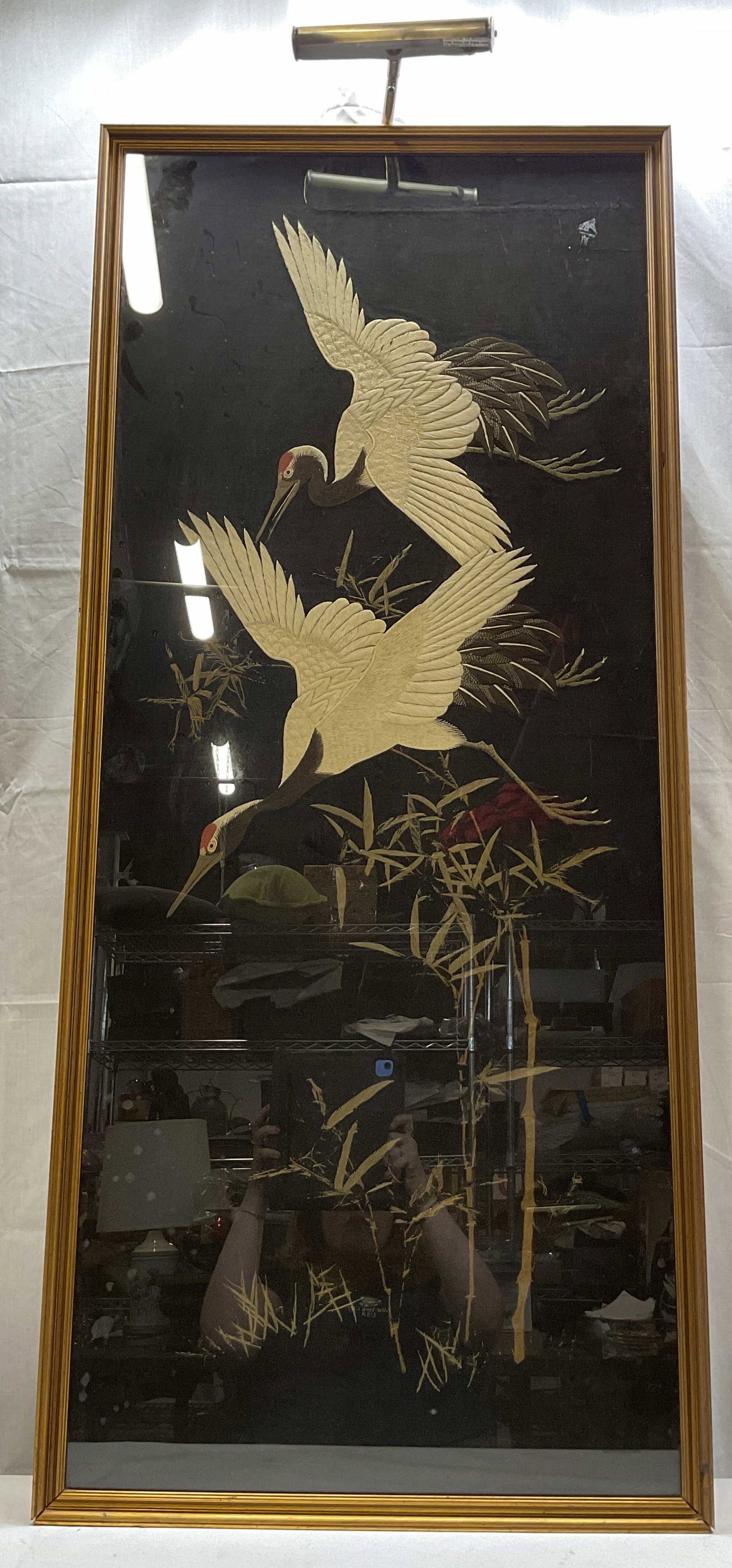 Vtg Chinese Embroidered Crane Frmd Wall Art Panel: Vintage Chinese embroidered crane framed wall art panel. Long rectangular gold toned frame. Comes with art light at the top. Embroidered imagery of two crane birds flying over stalks of bamboo. Varyin
