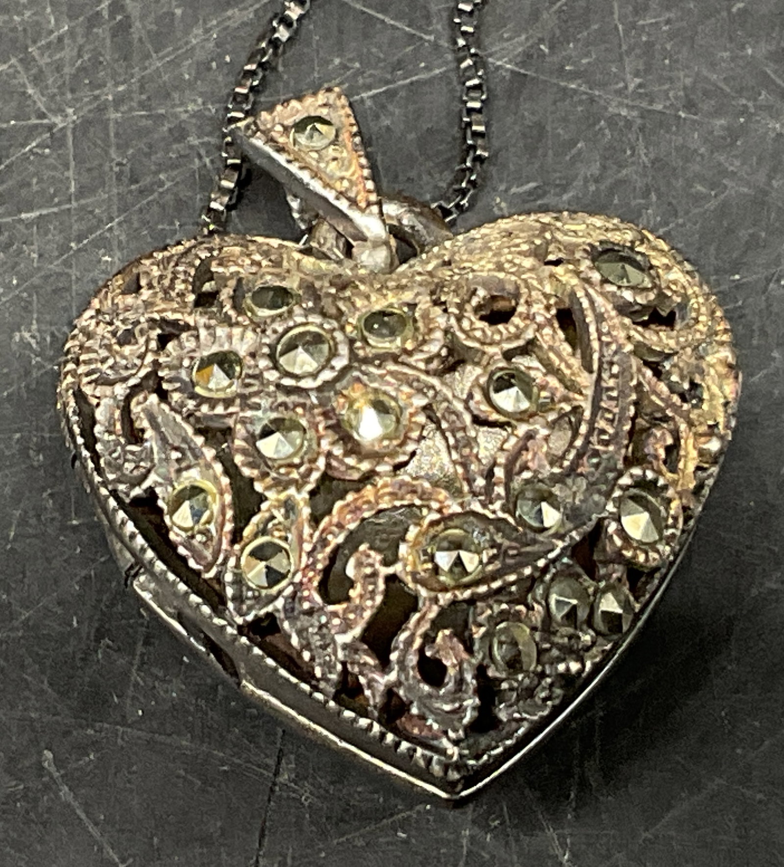 VTG-Sty STER Filigree Puffy Heart Locket Necklace: Vintage-Style Sterling Silver Filigree Puffy Heart Locket Necklace. Marcasite Accents. Charm and Chain Marked 925. Tarnishing Present. Measures app 11.75in L Chain and 1in L Pendant. Total Weight 11g.