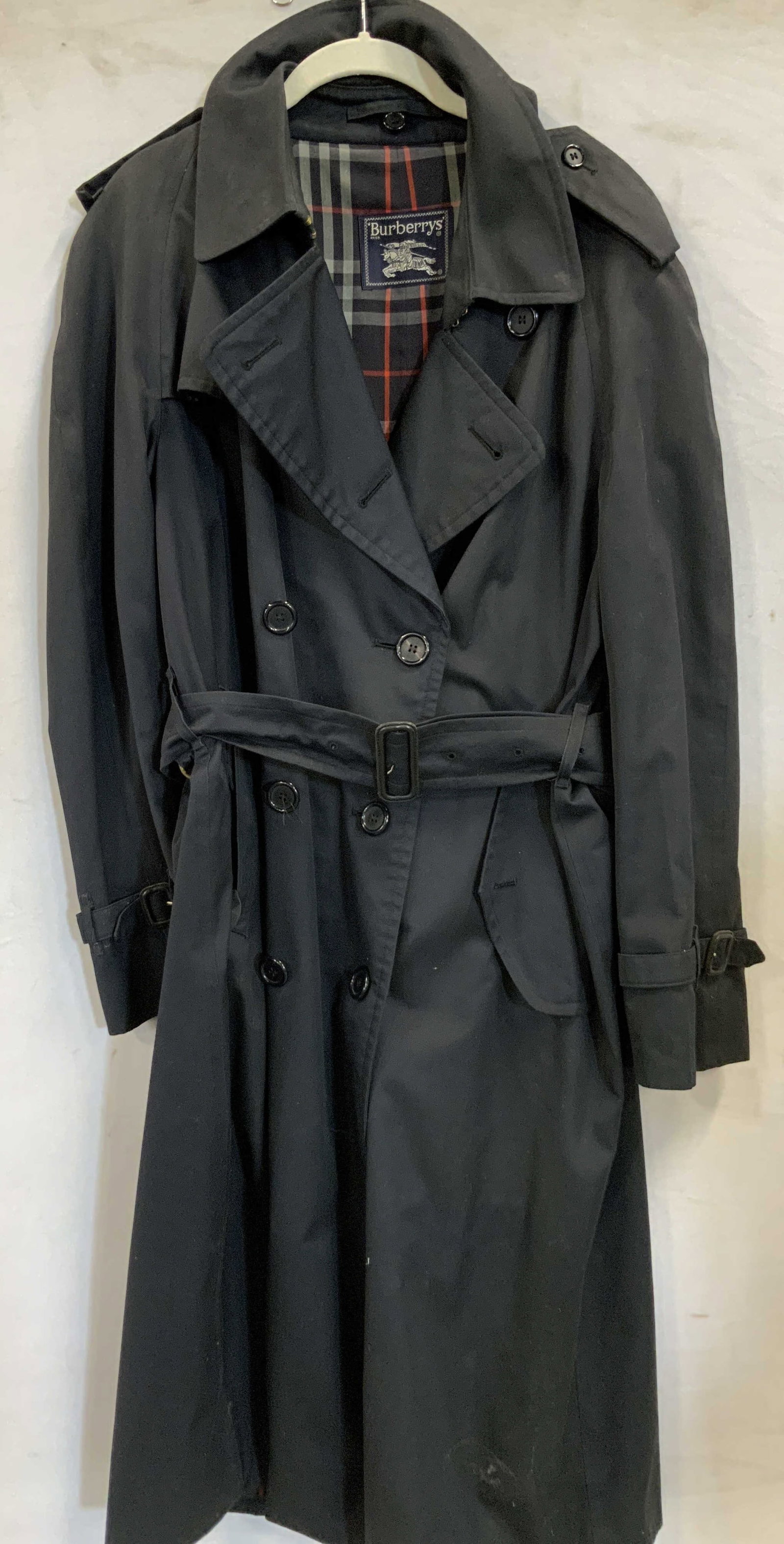 Vntg Burberrys double breasted trench coat 1990s: Vintage Burberrys double breasted trench coat. Made in the 1990s. Size 40R. Made of a cotton polyester blend. Coat features a dark navy outer shell complemented by the iconic plaid interior. Coat has