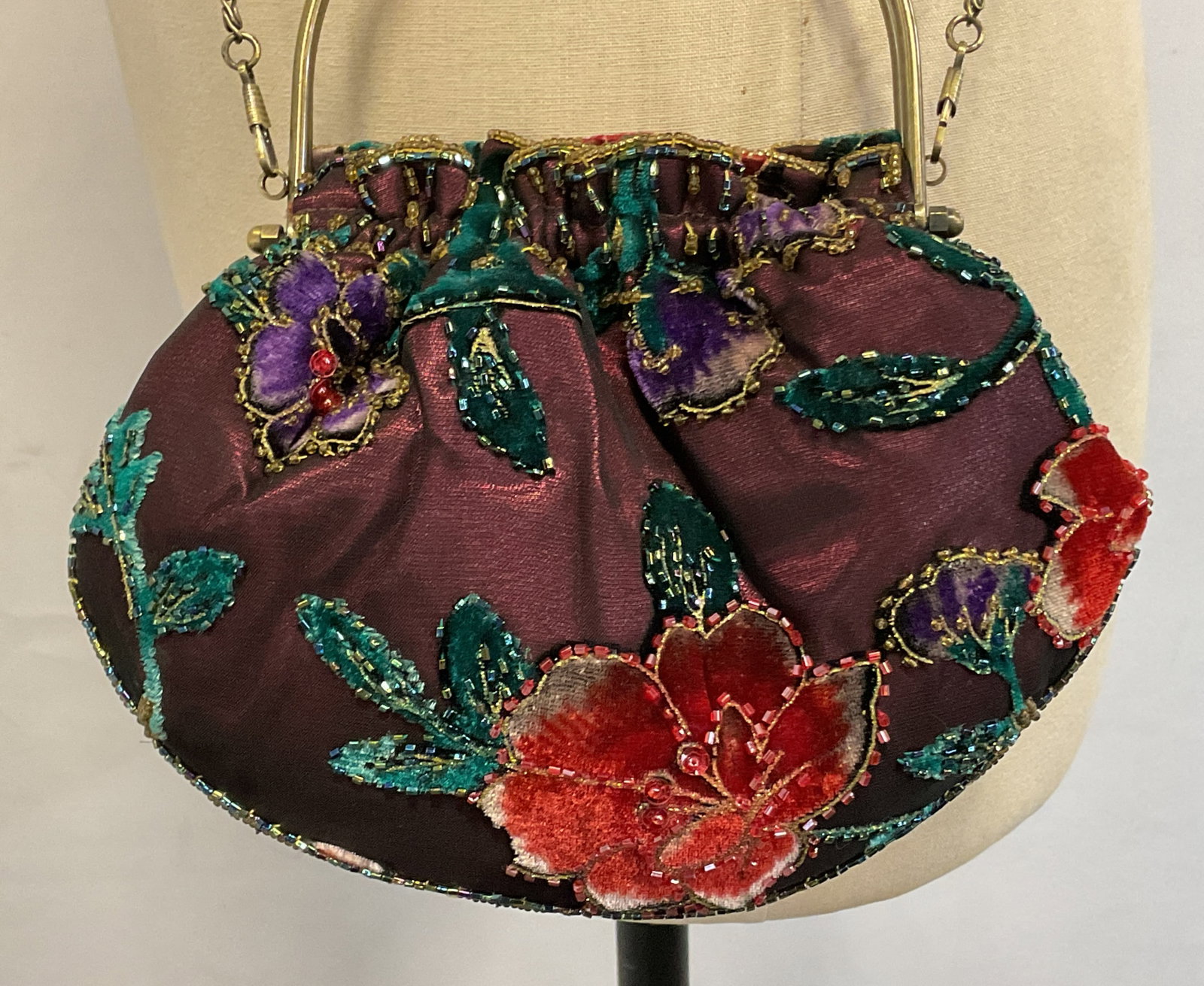 M & W Silk & Velvet Beaded Evening Bag: M & W silk and velvet beaded evening bag. Marked M & W on inside label. Ruffled scalloped trim. Purple red background. Velvet floral motifs in varying colors with beaded accents. Metal attached strap 
