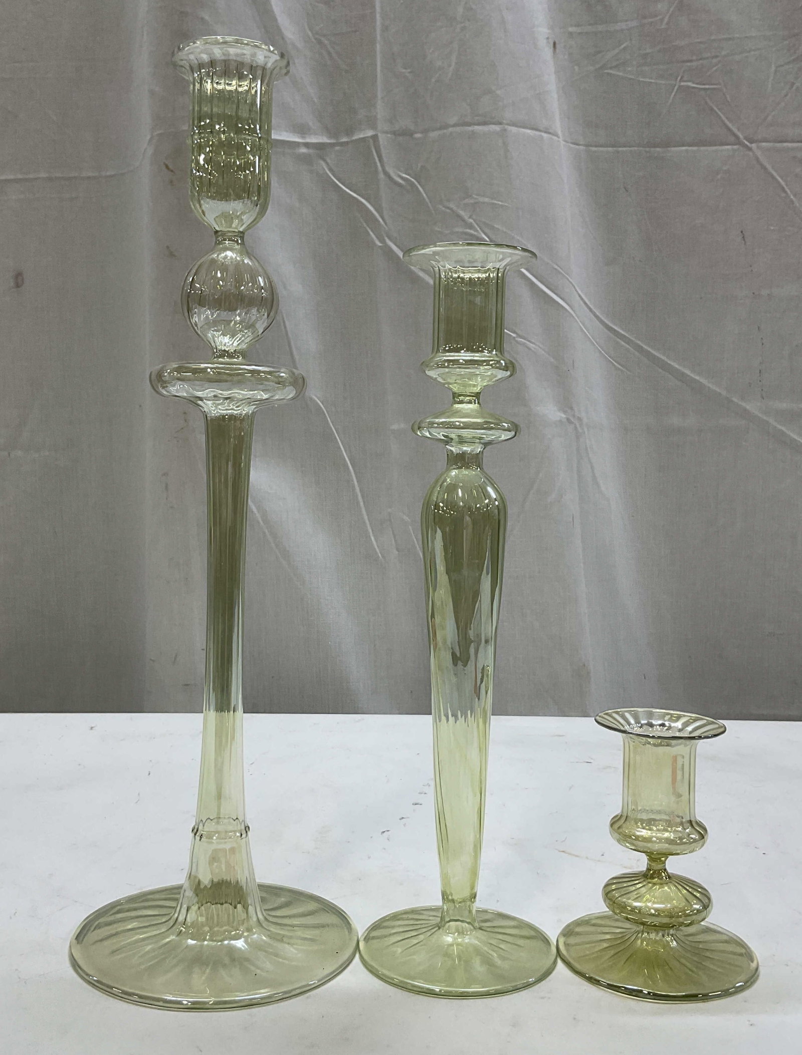 Lot 3 Hand Blown Art Glass Candlestick Holders: Lot of 3 hand blown art glass candlestick holders. Round bases with ribbed surface. Long and short stems. Round wide rims. Unique shapes. Lightweight and delicate. Light clear green color. All have
