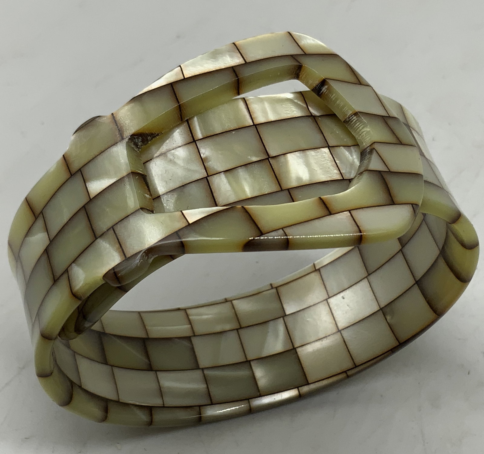 Vtg Mother of Pearl Mosaic Buckle Bracelet: Vintage artisan statement bangle bracelet designed in a wrapped belt buckle motif. Wide structured cuff is hand set with geometric grid mosaic of mother of Pearl shell tile panels. Features dark