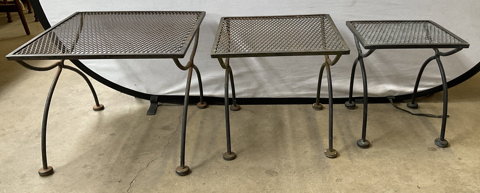 St3 Vtg MidC Wrought Iron Nesting Side Tables: Set of 3 vintage mid century wrought iron nesting patio side tables. Curved legs with round feet. Square tops with mesh design. Sizes vary. Largest measures approx 19.5 x 19.5 x 16 inches. Scratching 