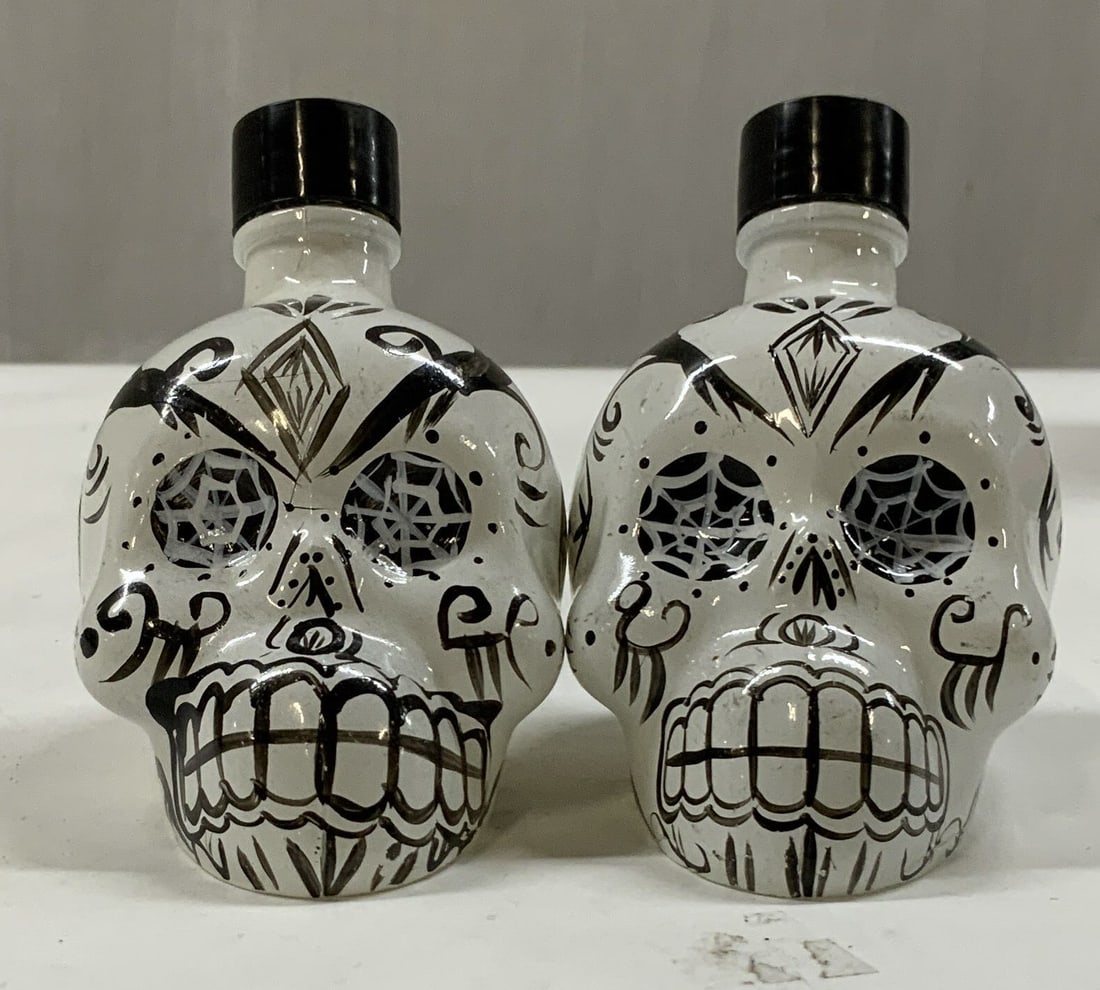 2 miniature glass day of the dead skull bottles: 2 miniature glass day of the dead skull bottles. Originally held 50ml of KAH Blanco Tequila now empty decorative pieces. White glass shaped like Himark skull with hand detailed black patterns and