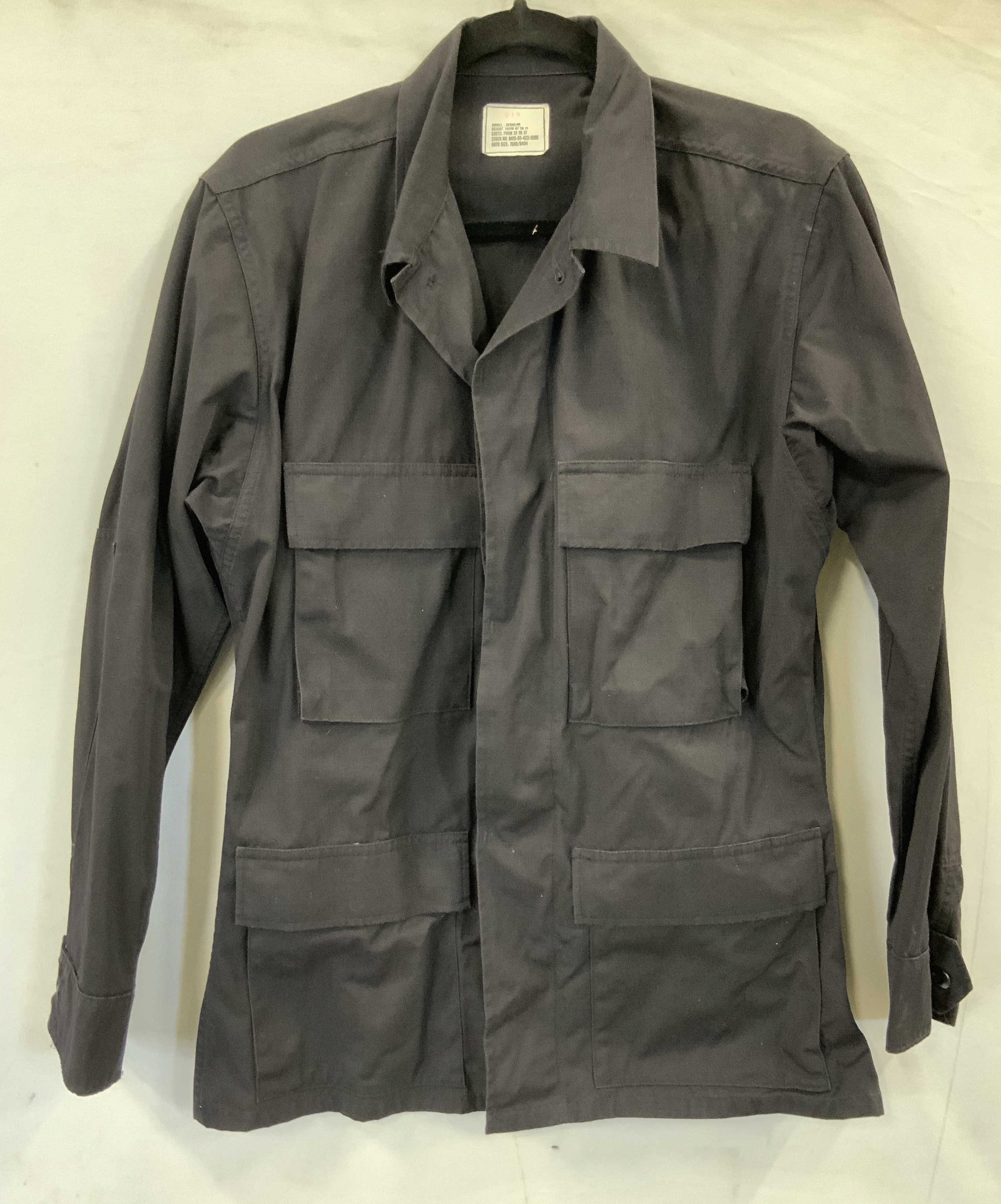 Black cargo jacket button closure and cuffs USA: Black cargo jacket with button closure. Made of a nylon cotton blend in the USA. Jacket features a button closure and button on sleeve cuffs. It has 2 front chest pockets and reinforced elbows. Size s